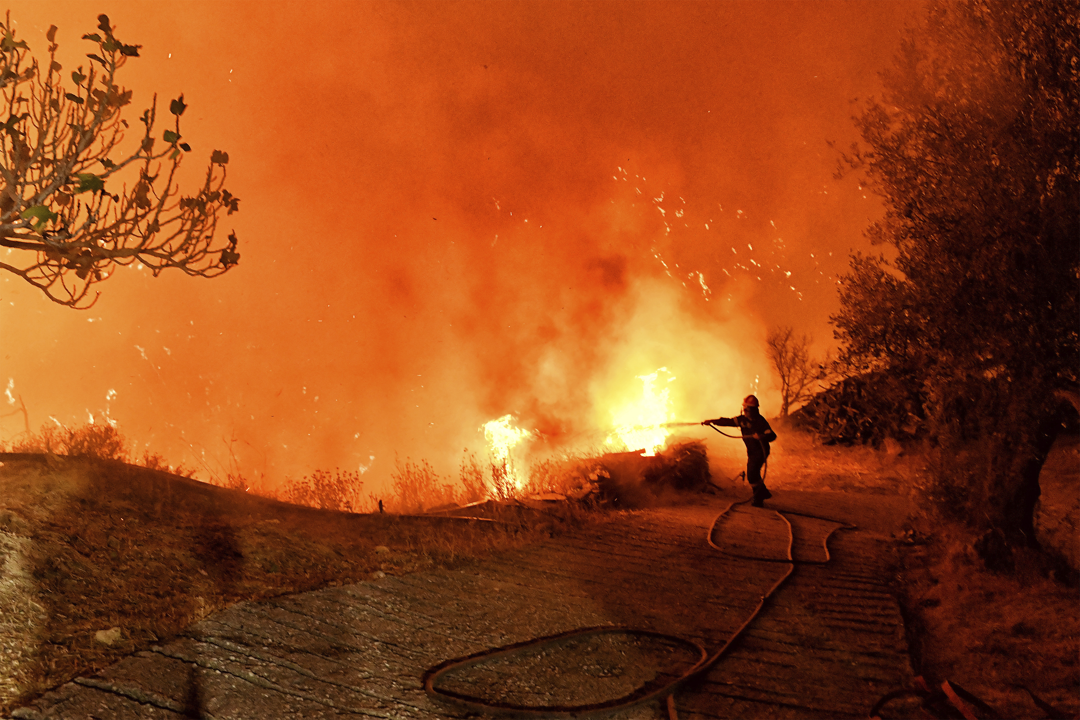 A firefighter tries to extinguish the flames near the village of Kallithea as fanned by strong winds raged uncontrolled despite the attempts of the authorities to stop the wildfire, some 149 kilometers (93 miles) west of Athens, Greece, in the region of Corinthia, late Sunday, Sept. 29