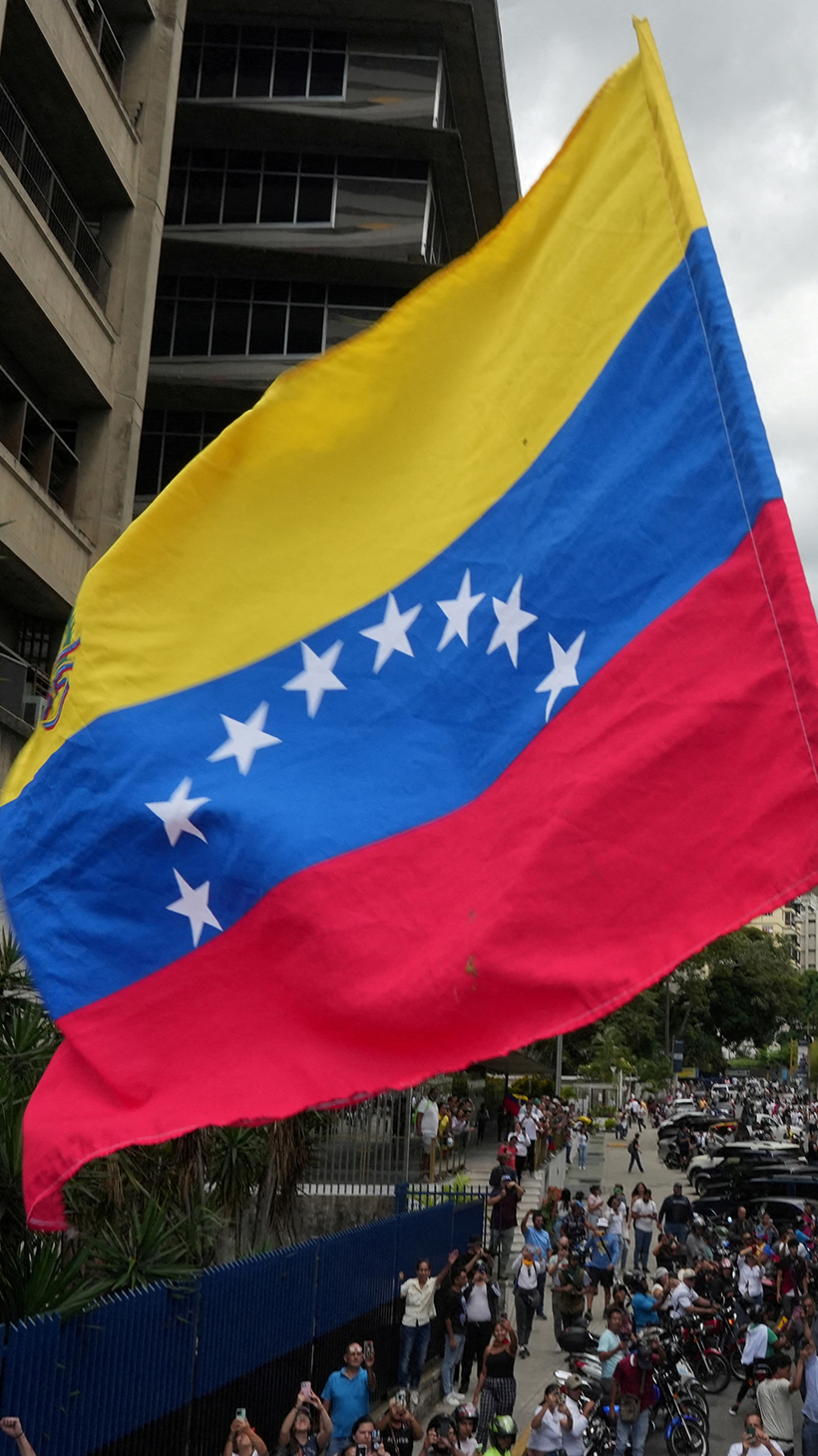 A protester waves a Venezuelan flag at an outdoor rally