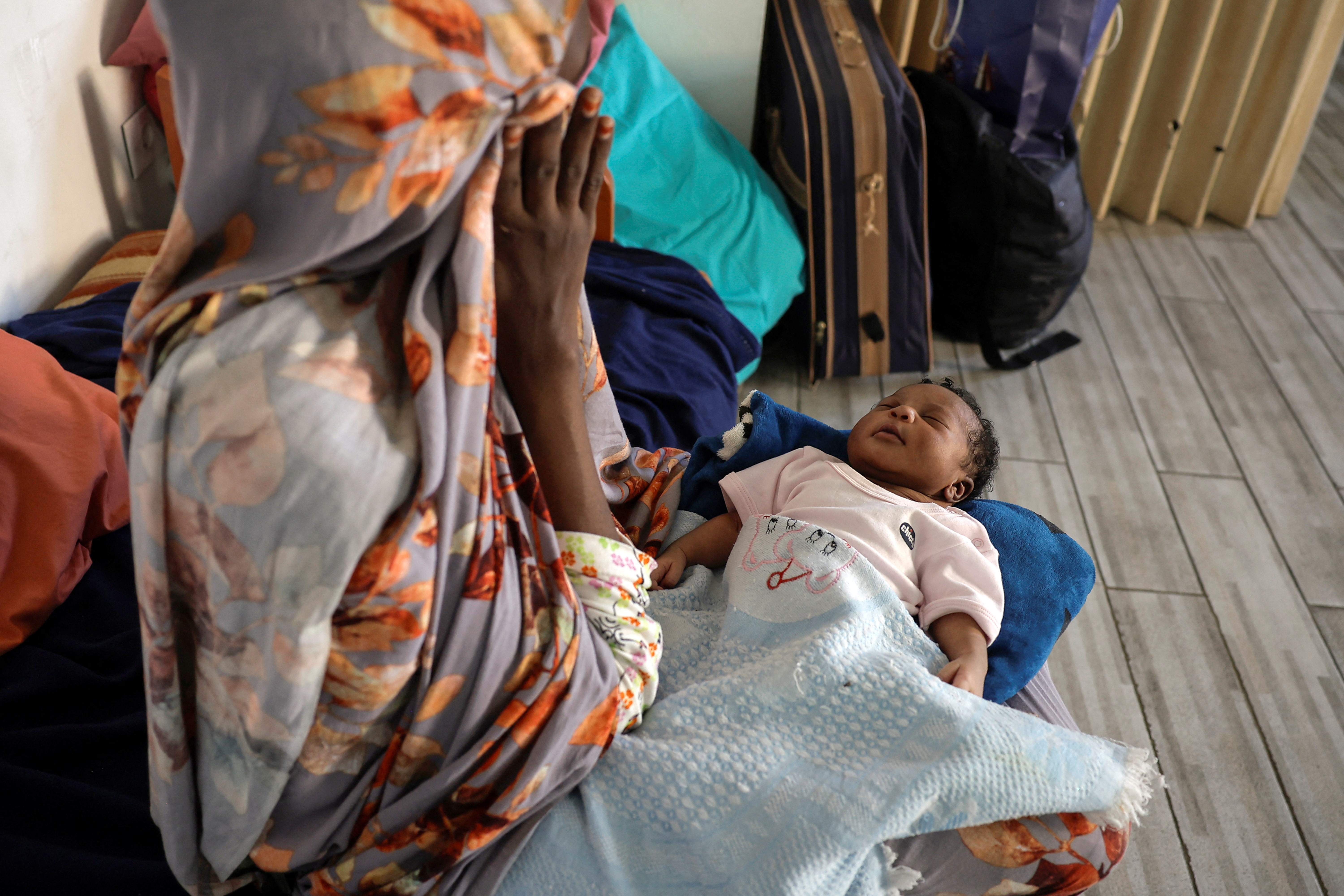 A migrant from Sudan holds her newborn baby girl in the temporary shelter for migrants in Beirut, Lebanon