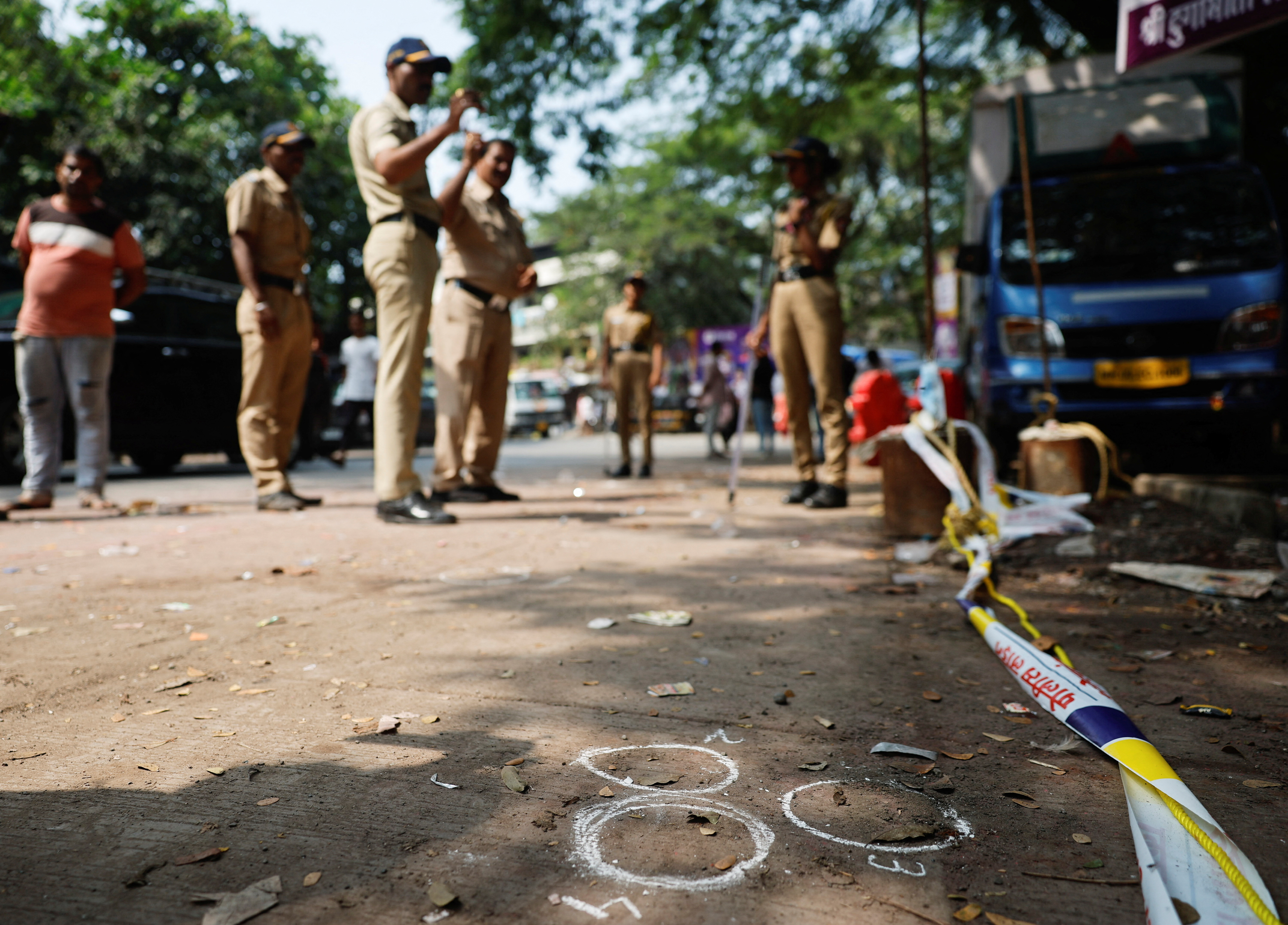 Police officers stand at the crime scene next to markings of the gunshots where Nationalist Congress Party (NCP) politician Baba Siddique was shot dead in Mumbai, India, October 13, 2024.