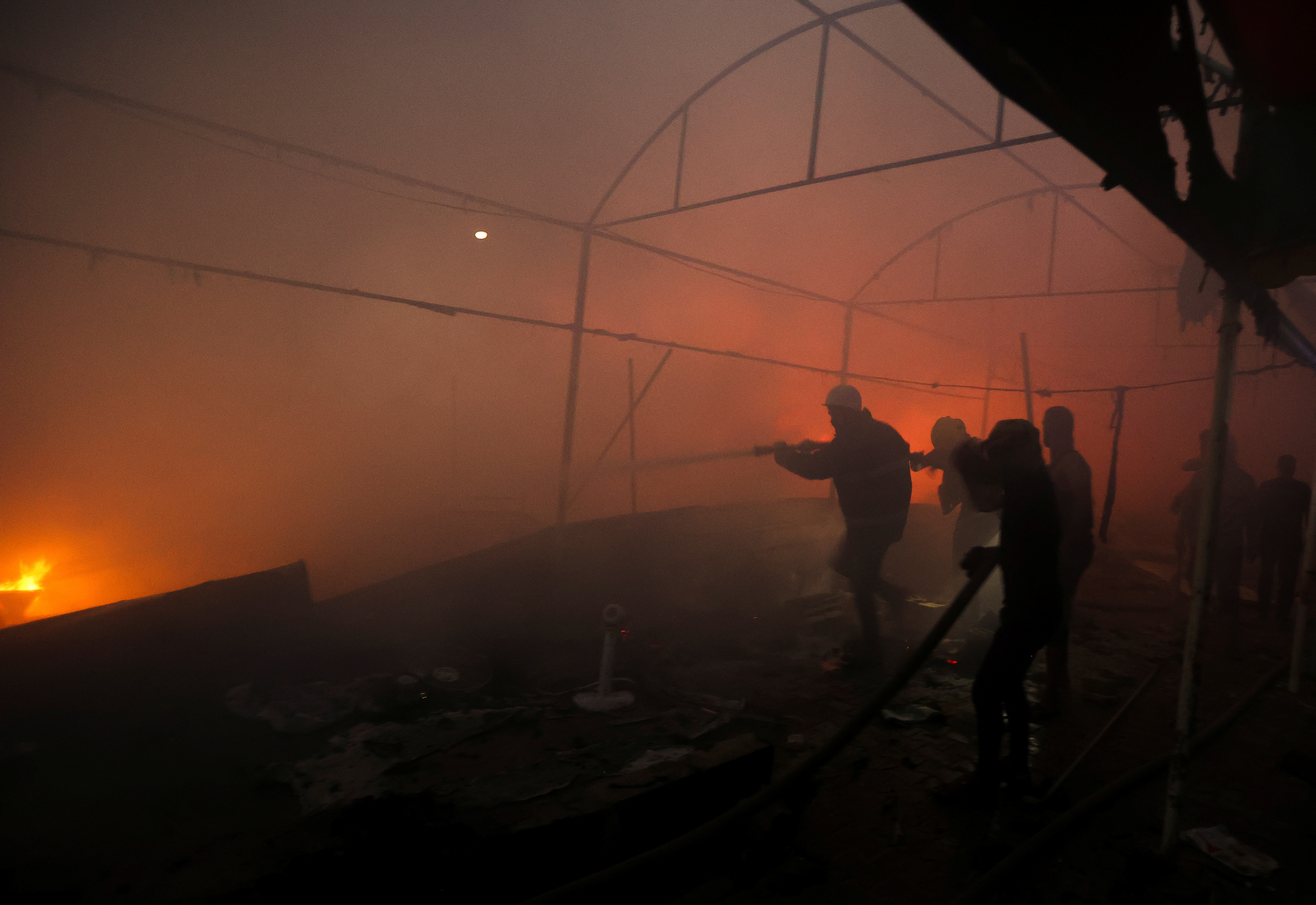 People attempt to extinguish a fire at the site of an Israeli strike on tents sheltering displaced people, amid the Israel-Hamas conflict, in Deir Al-Balah in the central Gaza Strip, October 14, 2024. REUTERS/Ramadan Abed