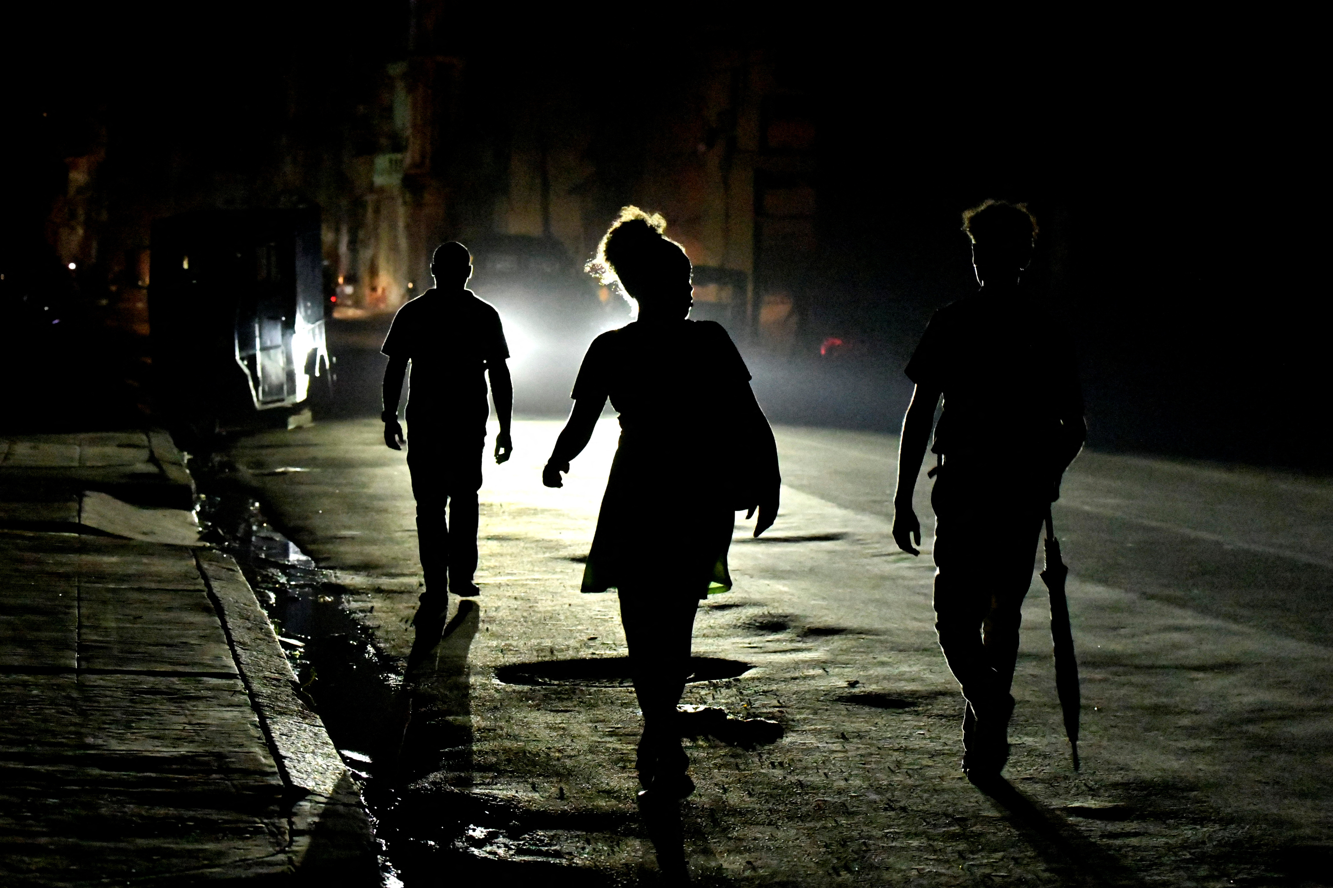 Three people walk down a darkened street during a blackout in Havana.