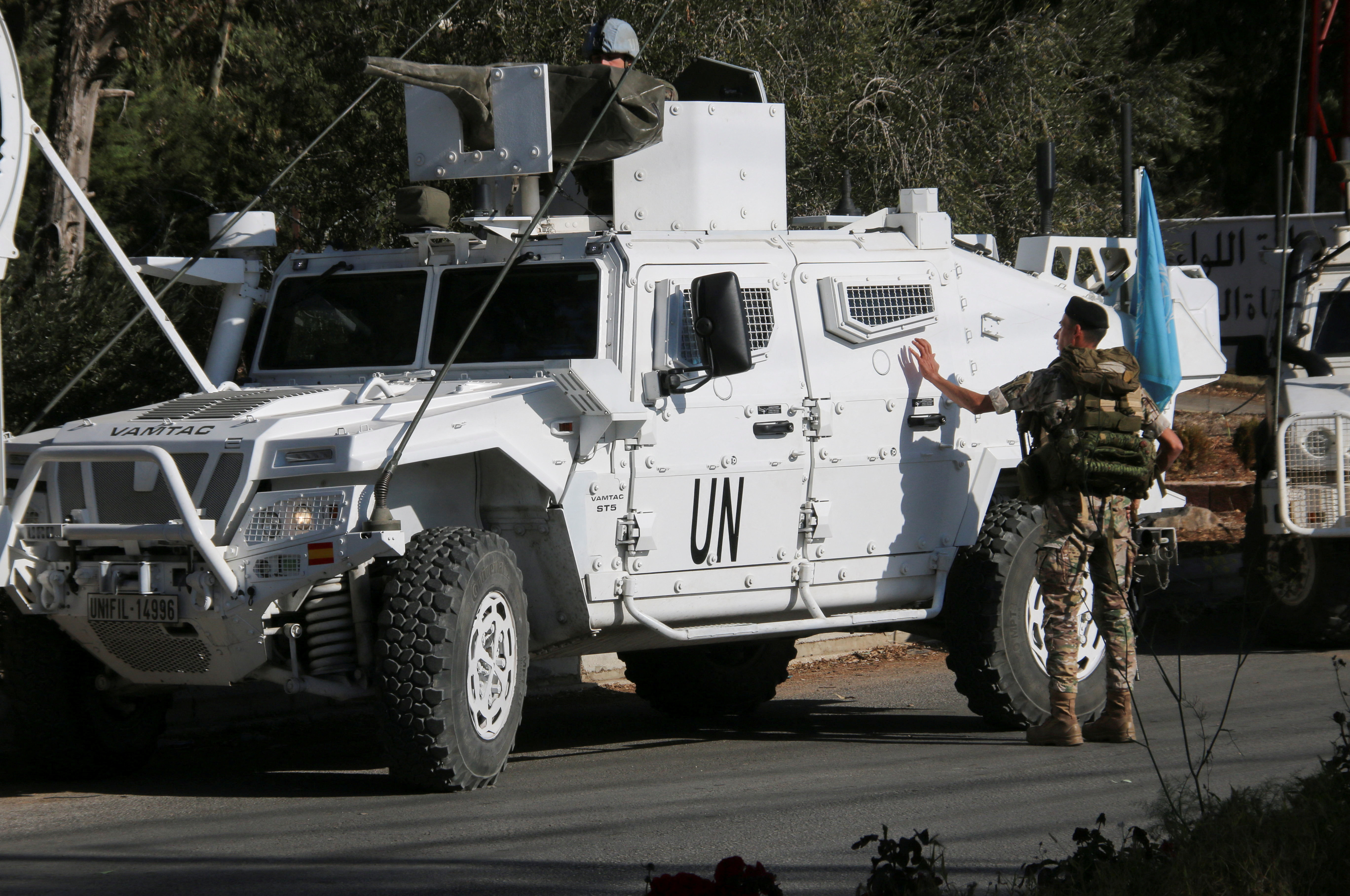 A Lebanese army soldier stands near UN peacekeepers (UNIFIL) vehicles