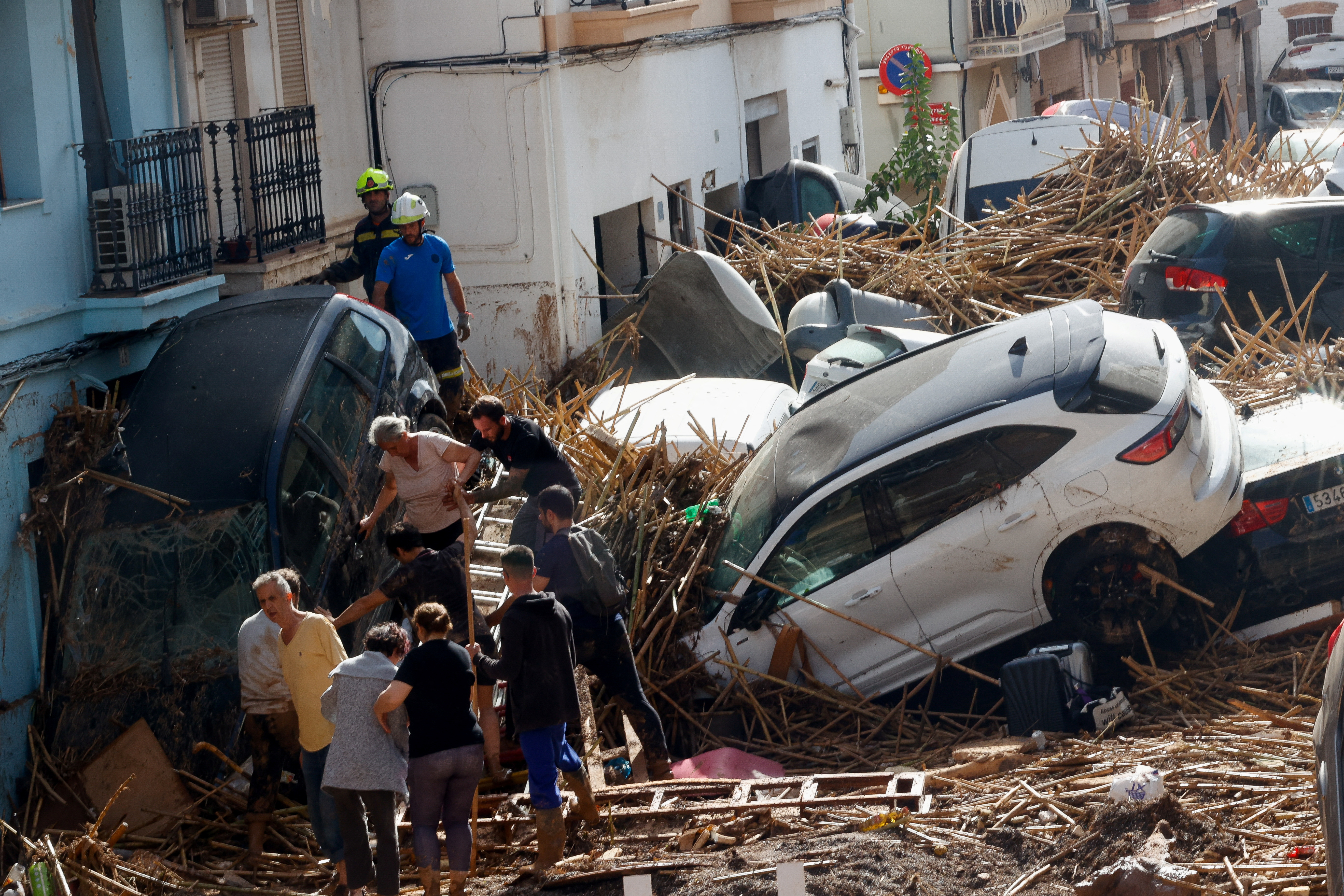 People work on a mud-covered street with damaged cars in the aftermath of torrential rains that caused flooding, in Paiporta, Spain, October 31, 2024. REUTERS/Eva Manez