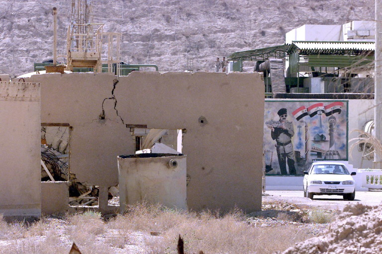 A car drives away from a mural showing Iraqi President Saddam Hussein on a wall of the Tammuz (Osirak) Iraqi nuclear reactor bombed by Israel during an air raid in 1981, and later hit in the 1991 Gulf War, at al-Toweitheh, some 30 kilometers (18 miles) southeast of Baghdad 09 September 2002. Iraq denied it had resumed activities at nuclear sites inspected by UN experts in the past and took the journalists on a tour to refute allegations to the contrary. AFP PHOTO/Ramzi HAIDAR (Photo by RAMZI HAIDAR / AFP)
