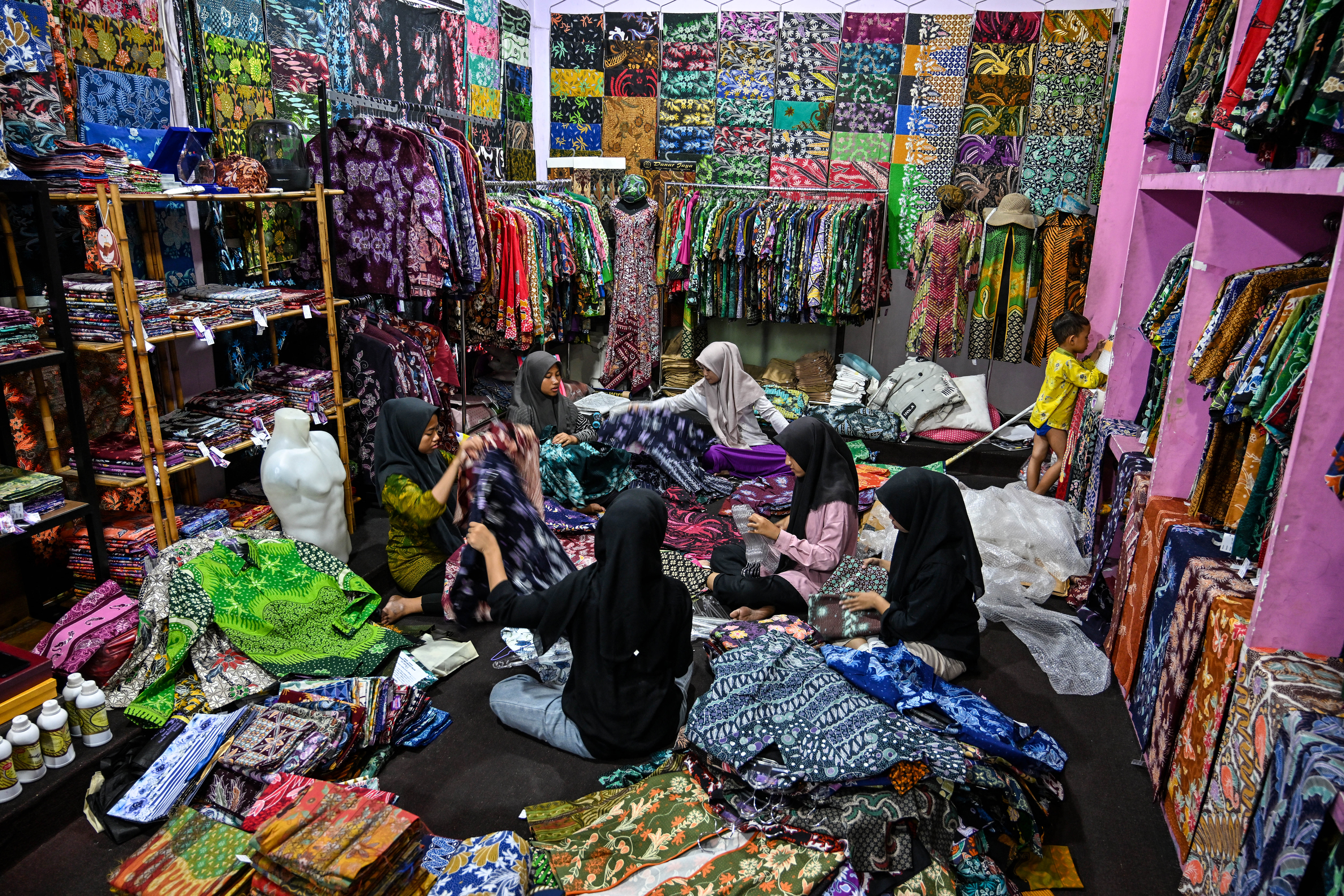 Students and workers arrange finished batik cloth with batik designs, a traditional textile dyeing technique using wax, at a gallery in the Sari Kenongo workshop in Sidoarjo during Indonesia's National Batik Day on October 2, 2024. (Photo by JUNI KRISWANTO / AFP)