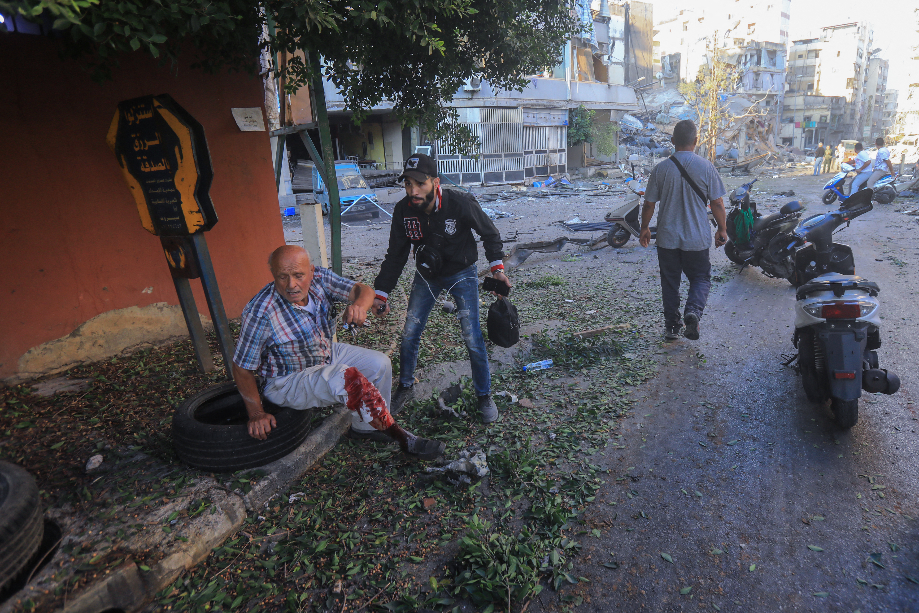 An injured resident sits on a sidewalk during Israeli airstrikes on the Mreijeh neighbourhood in Beirut's southern suburbs on October 4