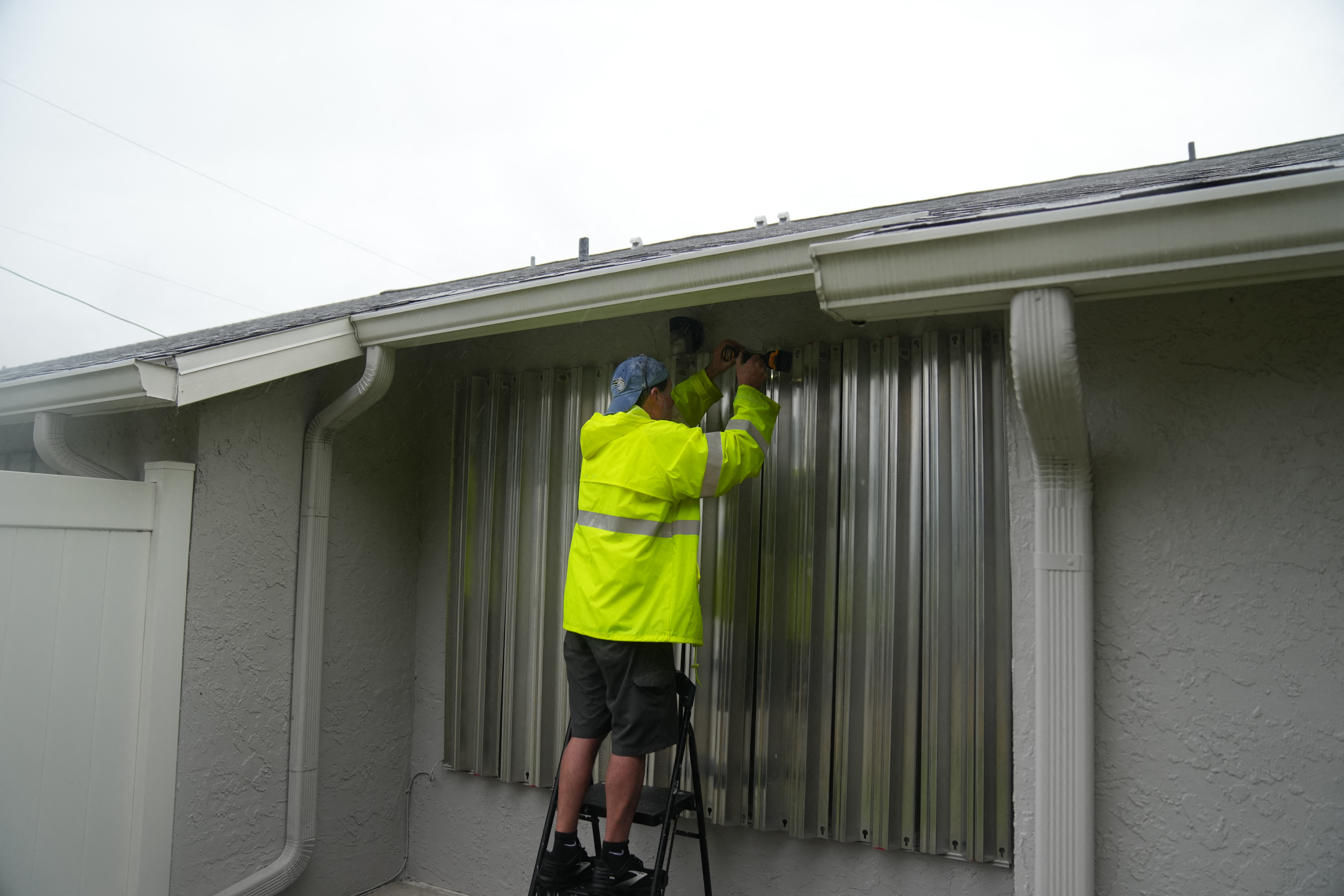 A resident secures aluminum shutters across windows in Dunedin ahead of Hurricane Milton's expected landfall tonight on October 9, 2024 in Florida