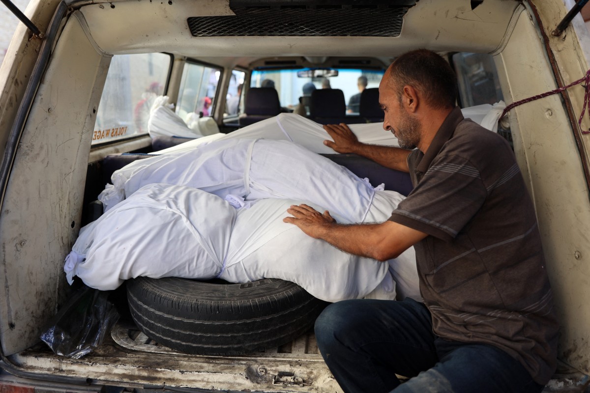 A man mourns over the bodies of a relatives killed in an overnight Israeli airstrike in the Jabalia refugee camp in the northern Gaza Strip, in front of the al-Maamadani on October 12, 2024. - In recent days, the military has launched an intense ground and air assault in northern Gaza, particularly in and around the city of Jabalia. (Photo by Omar AL-QATTAA / AFP)