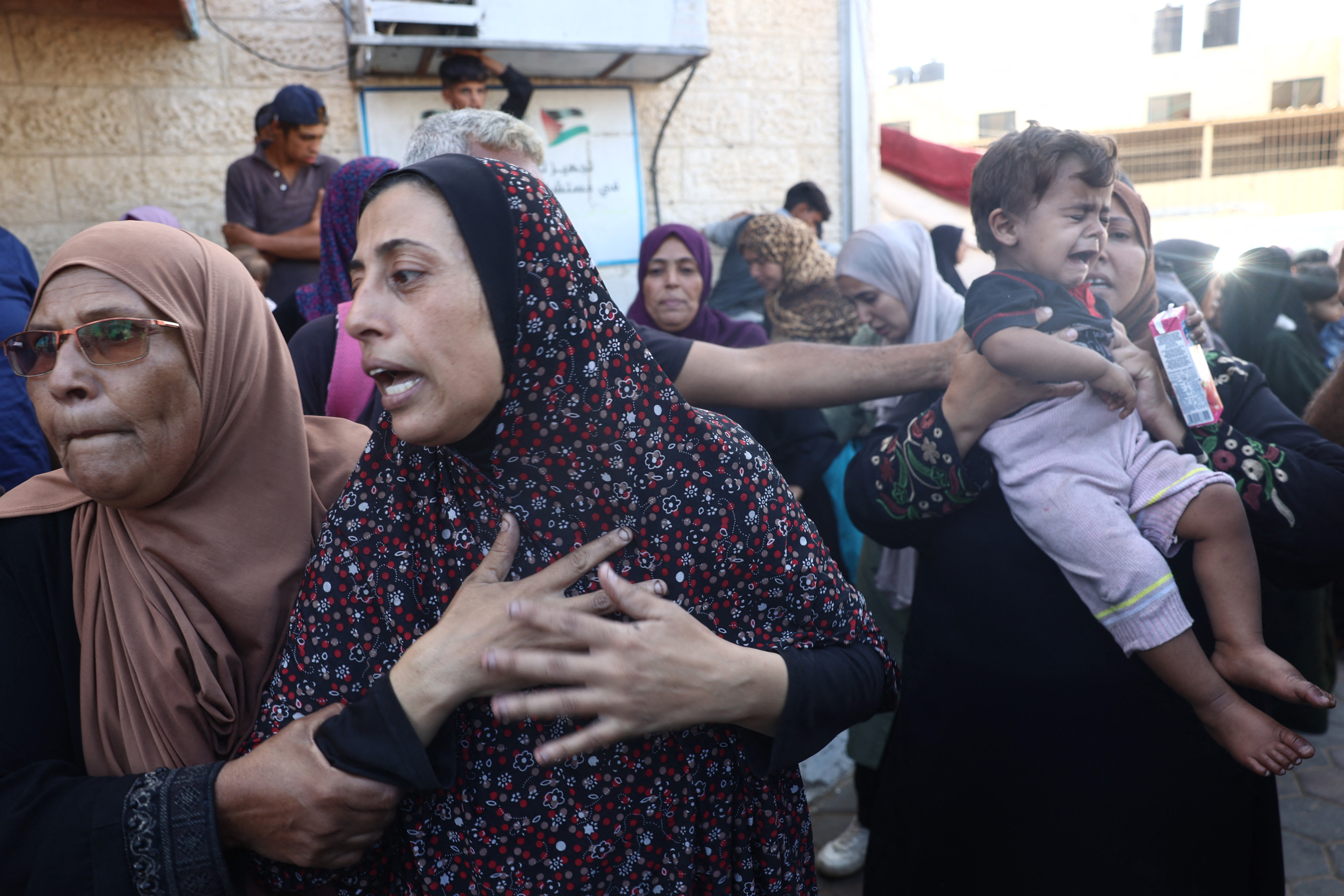 A Palestinian family, gathered at Al-Aqsa Martyrs Hospital in Deir el-Balah, mourn relatives killed in an Israeli attack on the Bureij refugee camp