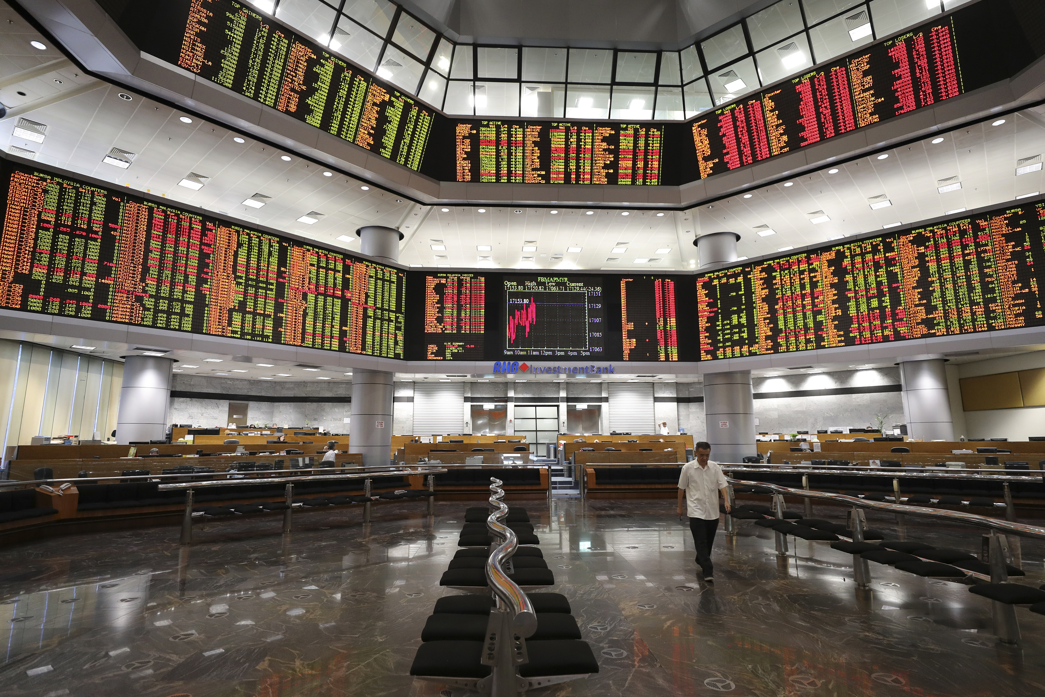 An investor walks in front of stock trading boards