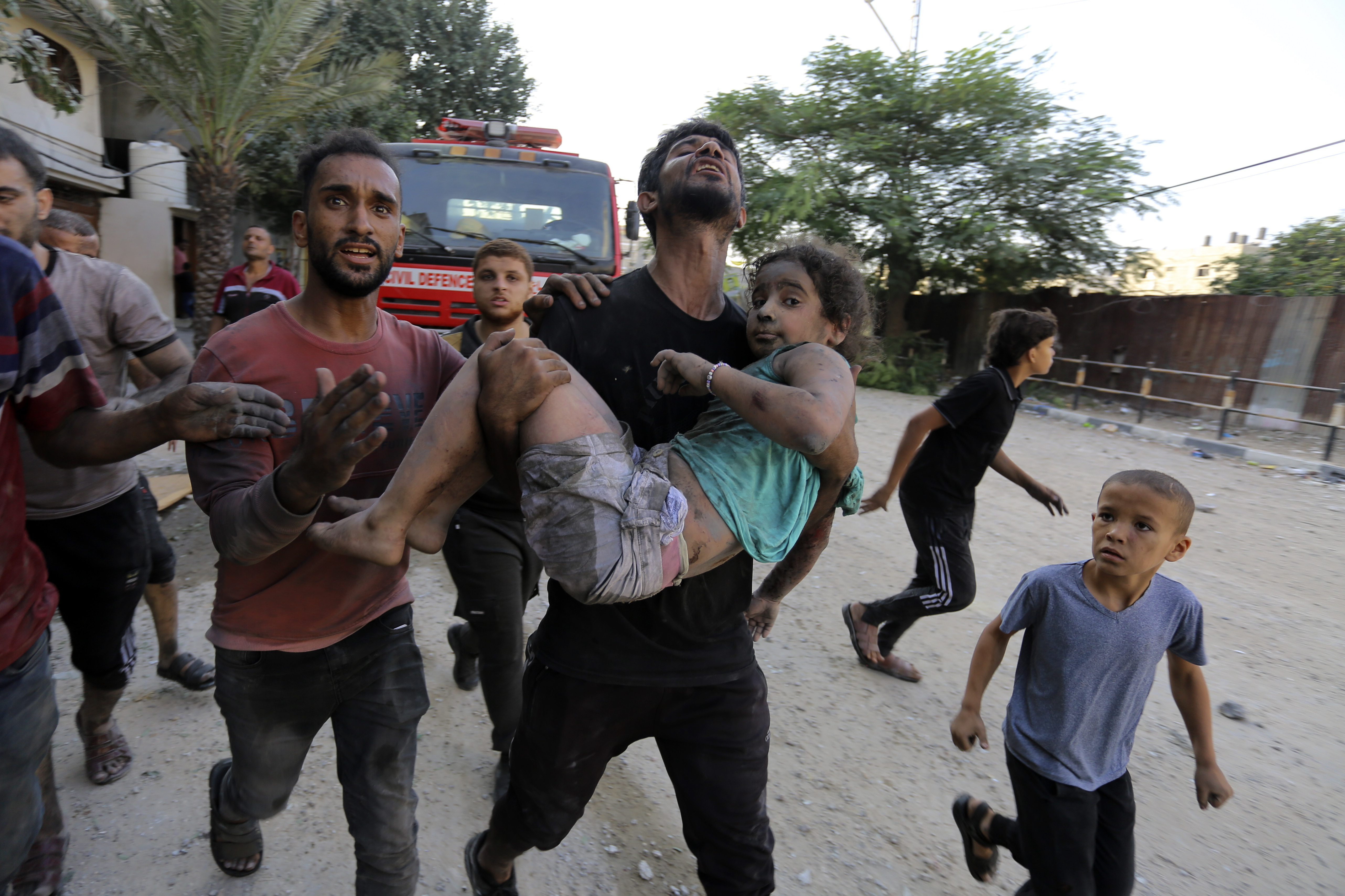 Palestinians carry a wounded girl after being rescued from under the rubble of buildings that were destroyed by Israeli airstrikes in Jabaliya