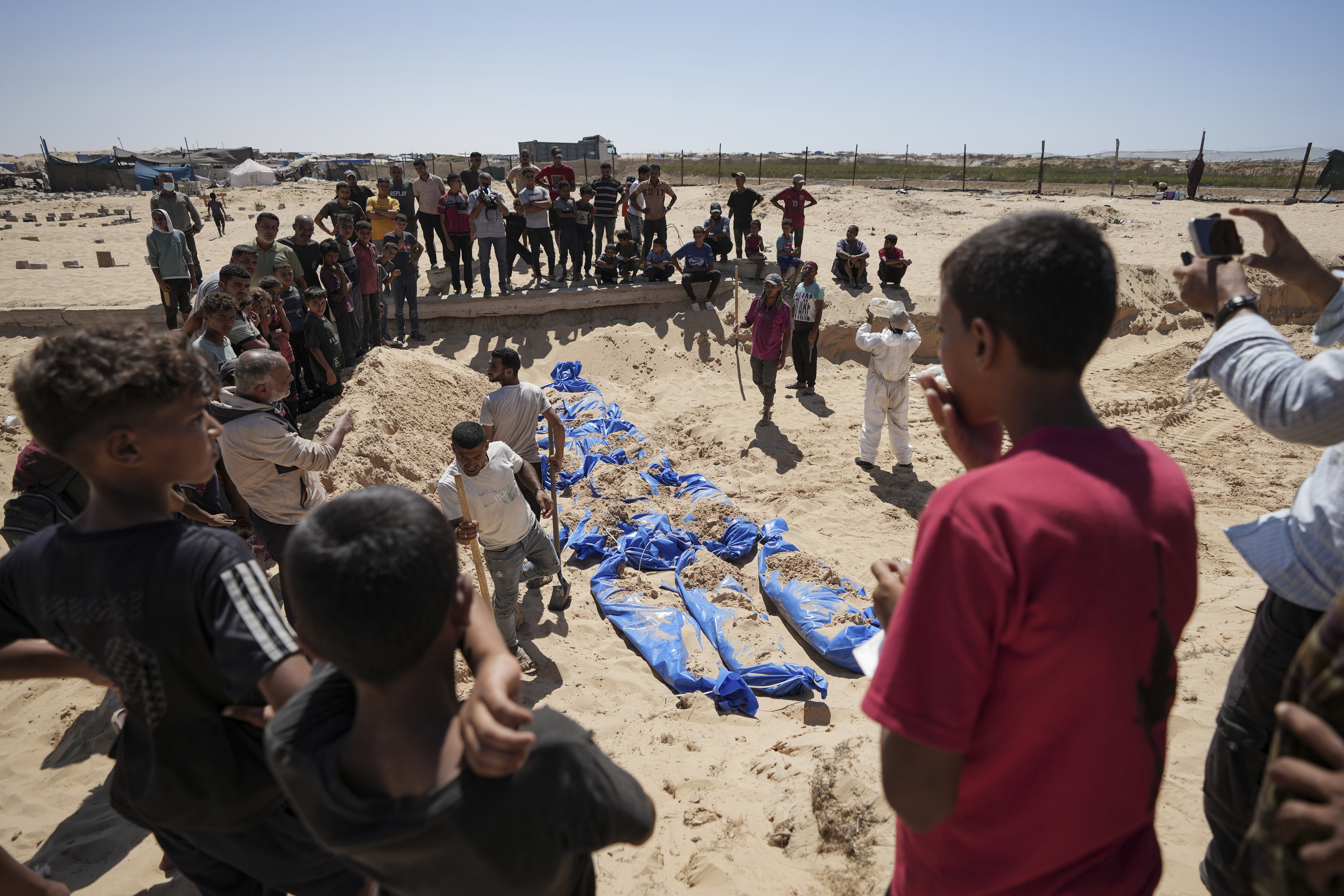 Workers bury bodies returned by Israel in a cemetery in Khan Younis