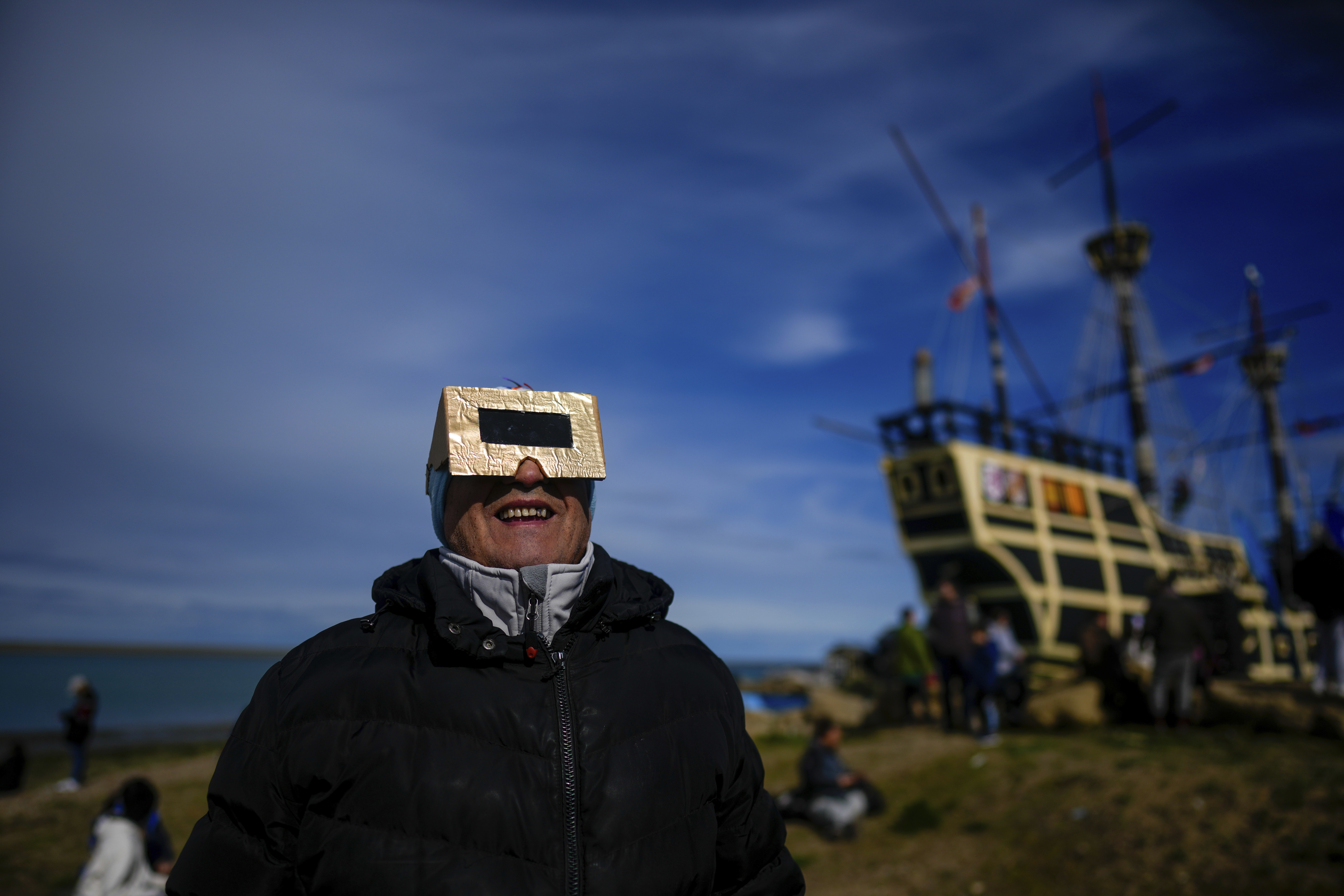 A person watches the eclipse through boxy glasses.