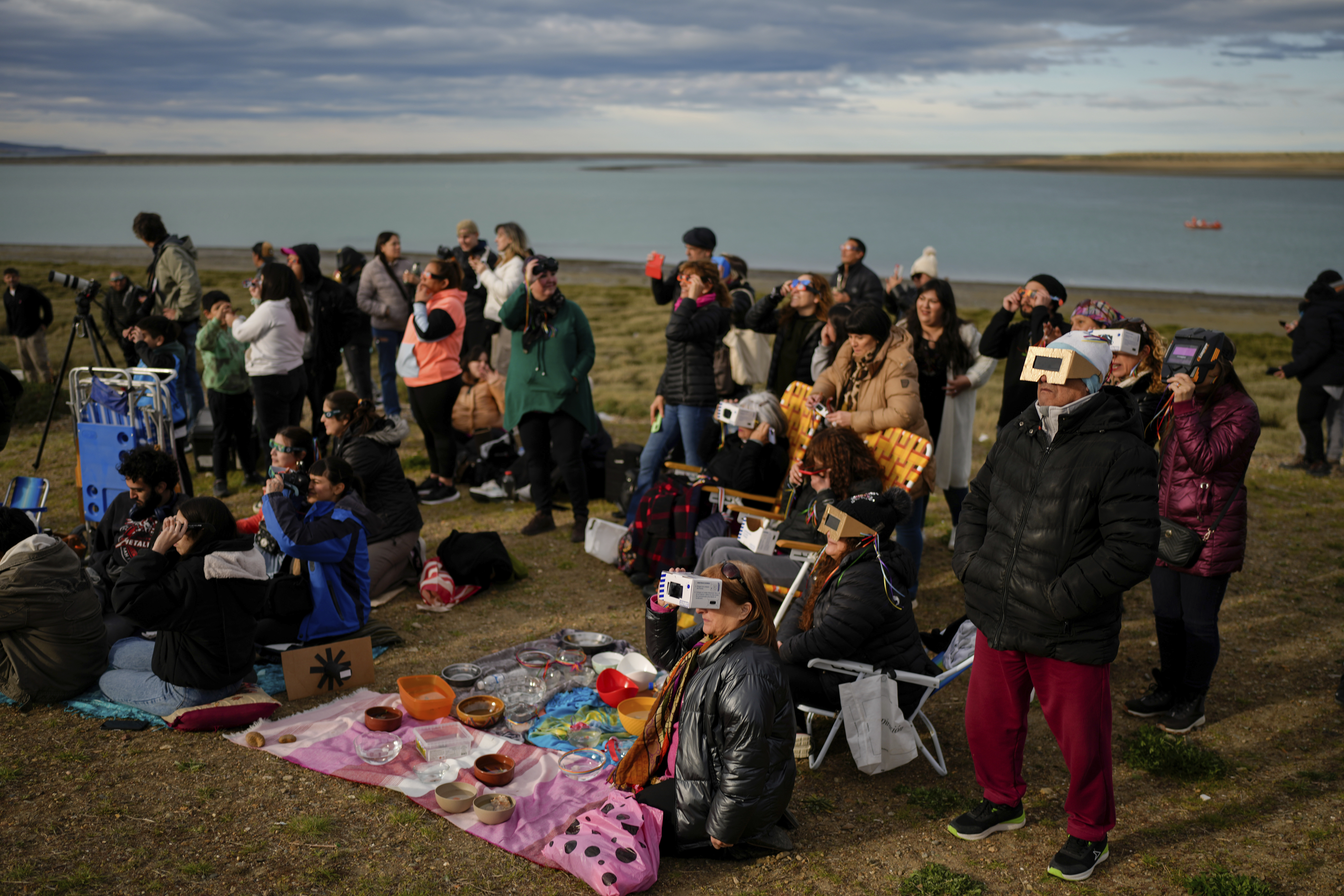 A group of people on a beach watch the eclipse.