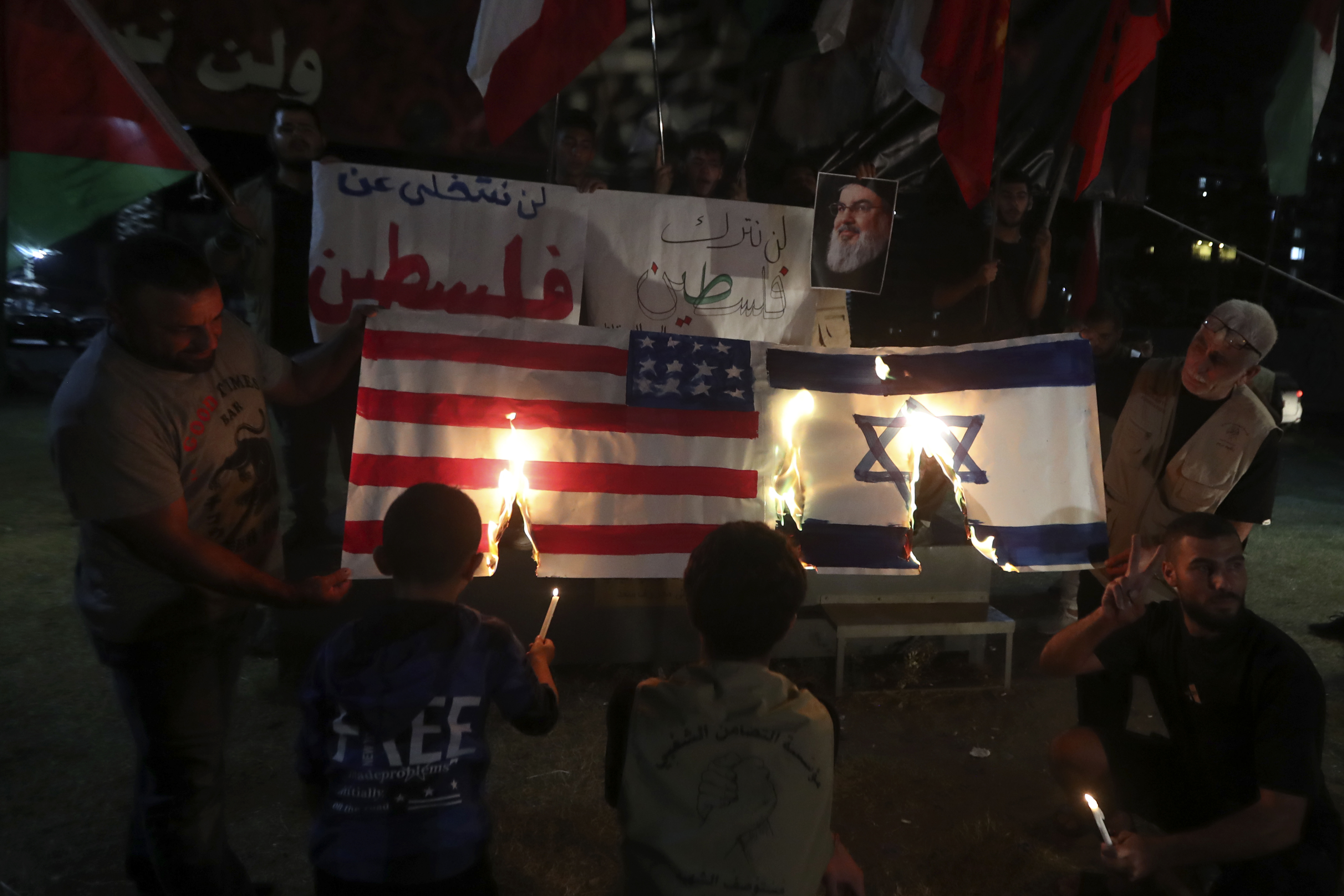 Lebanese and Palestinians burn a representation of the Israeli and U.S. flags during a commemoration marking the one-year anniversary of the Israel-Hamas war in the southern port city of Sidon, Lebanon, Monday, Oct. 7