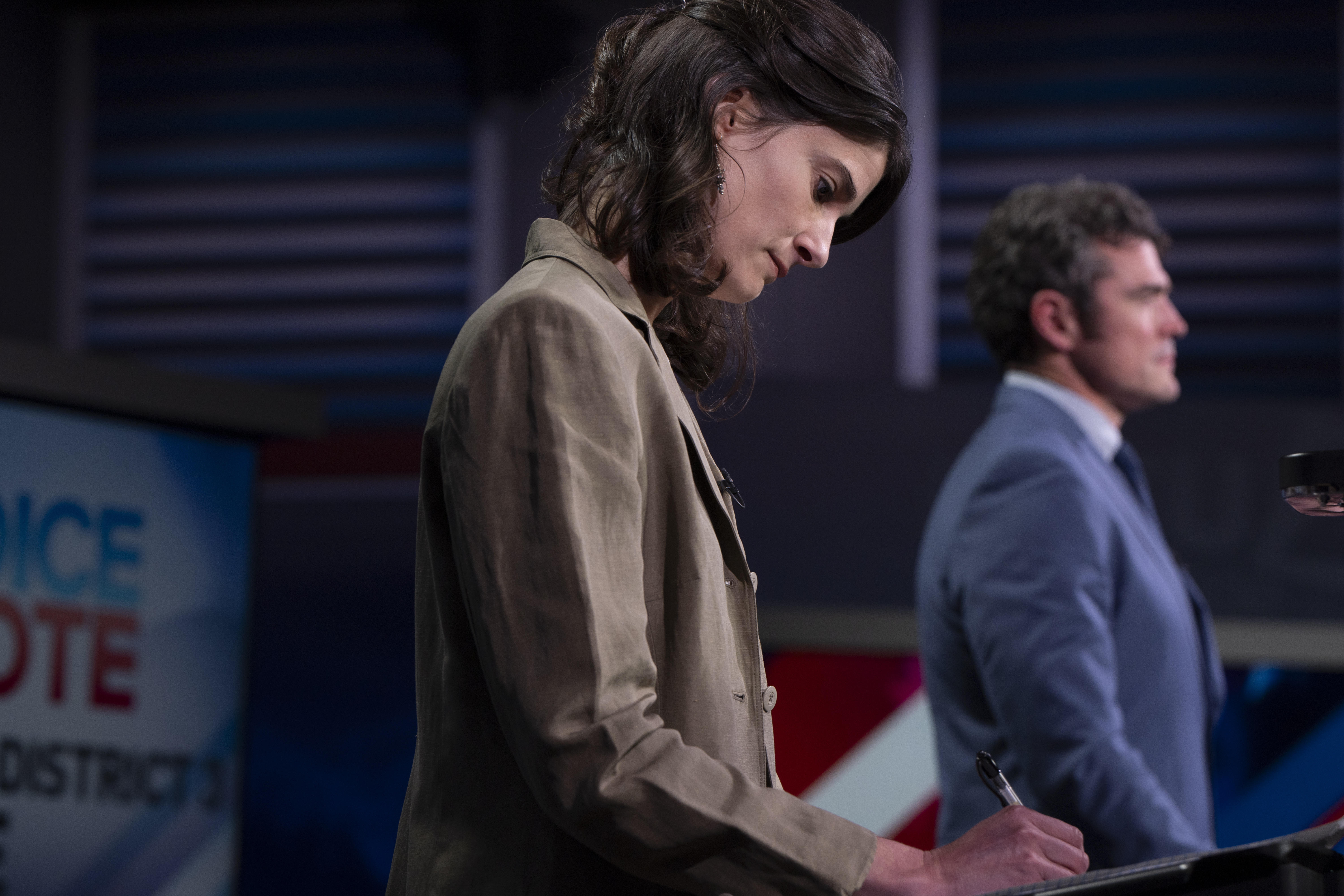 Marie Gluesenkamp Pérez looks downward at her podium as she prepares to debate her rival Joe Kent