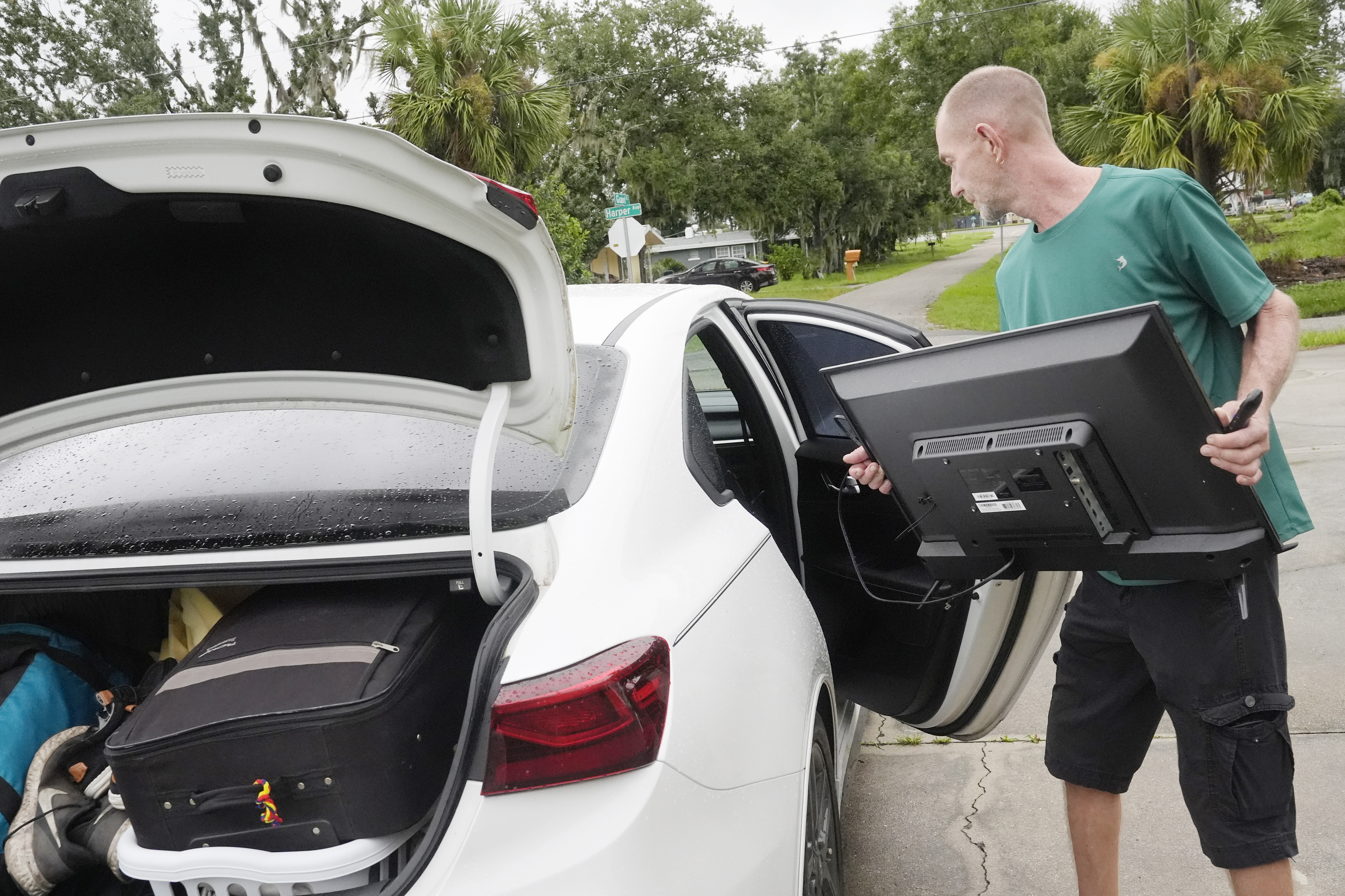 Josh Parks loads his television in his car as he prepares to evacuate to his daughters home in advance of Hurricane Milton, Wednesday, Oct. 9, 2024, in Port Charlotte, Fla