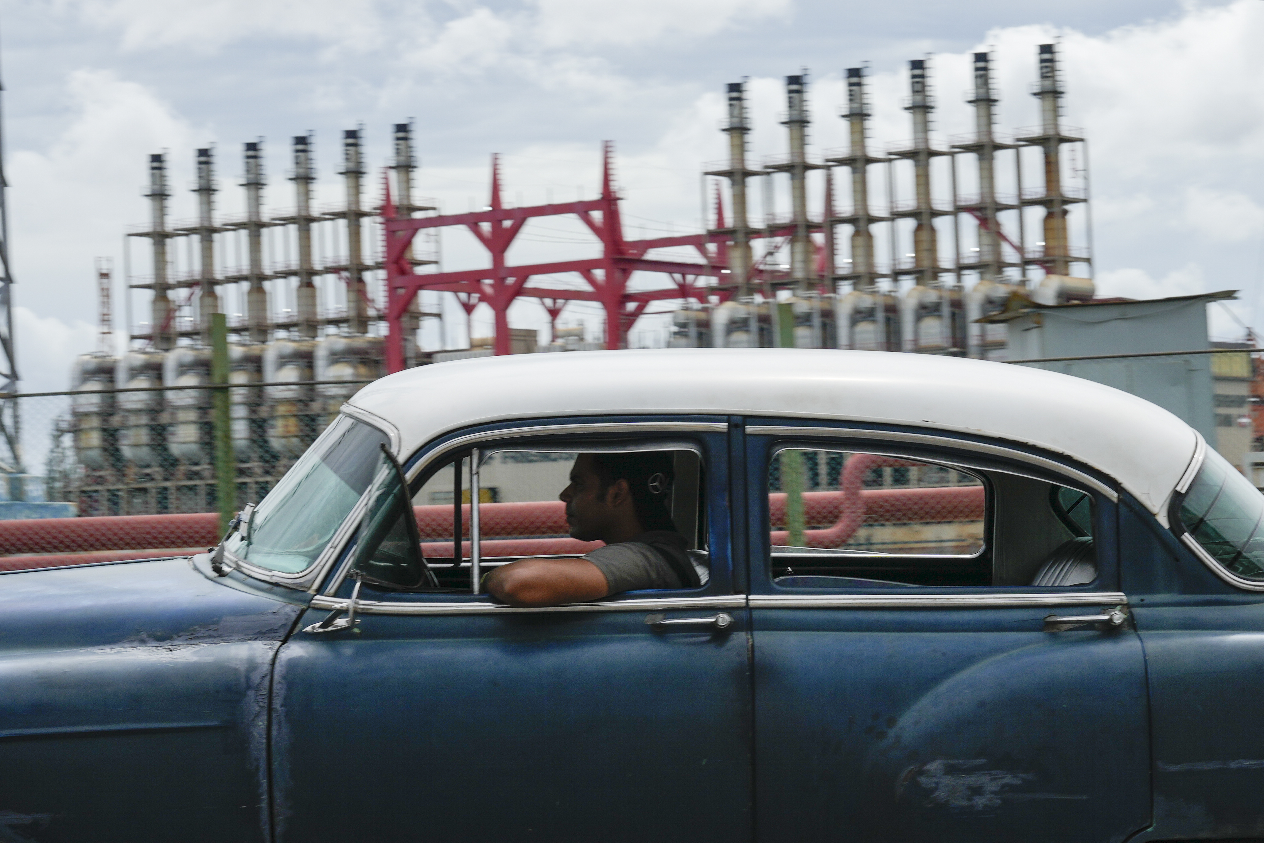 A classic car rolls past a generator in Havana during a blackout.