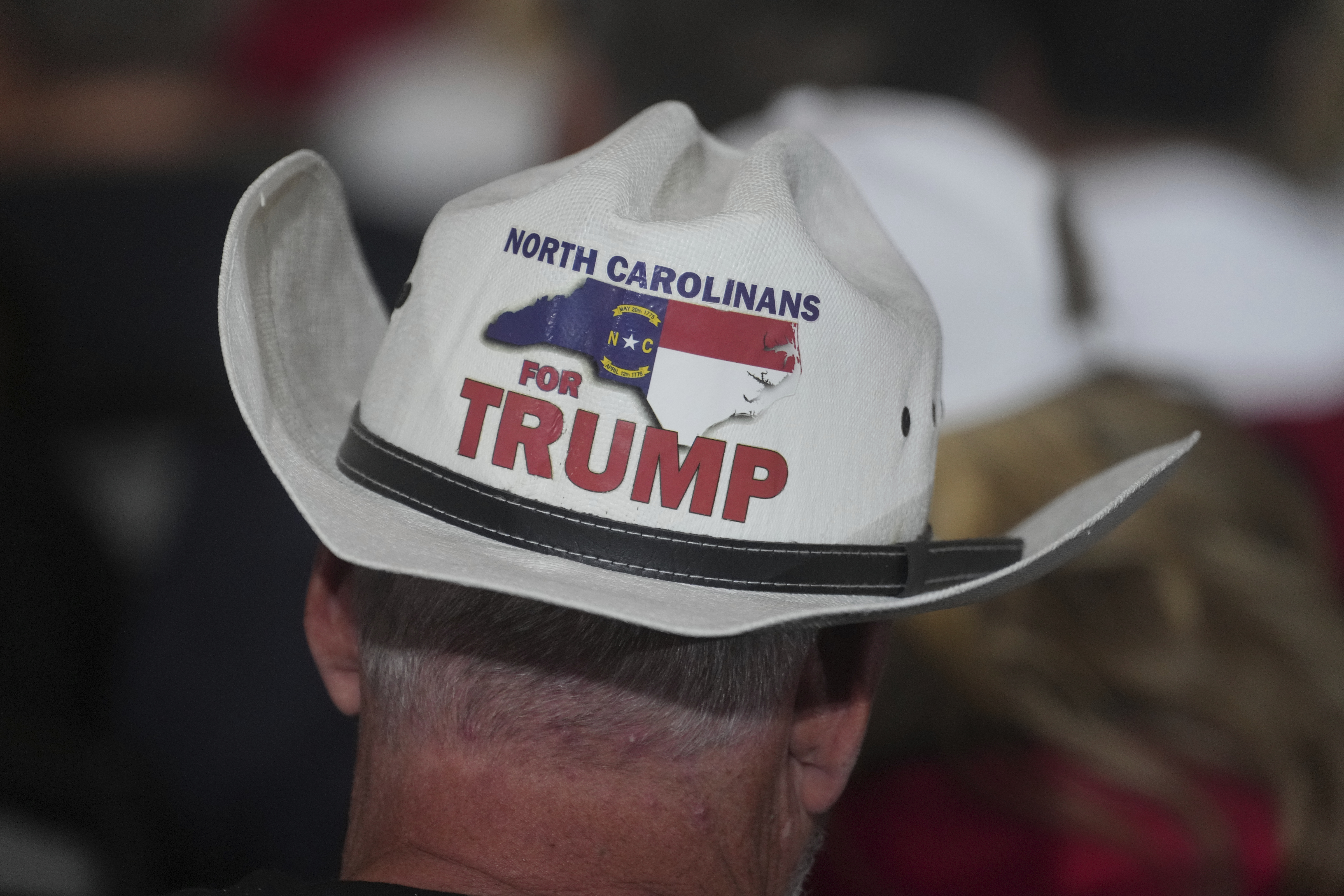 A man wears a cowboy hat that reads "North Carolinians for Trump" on the back