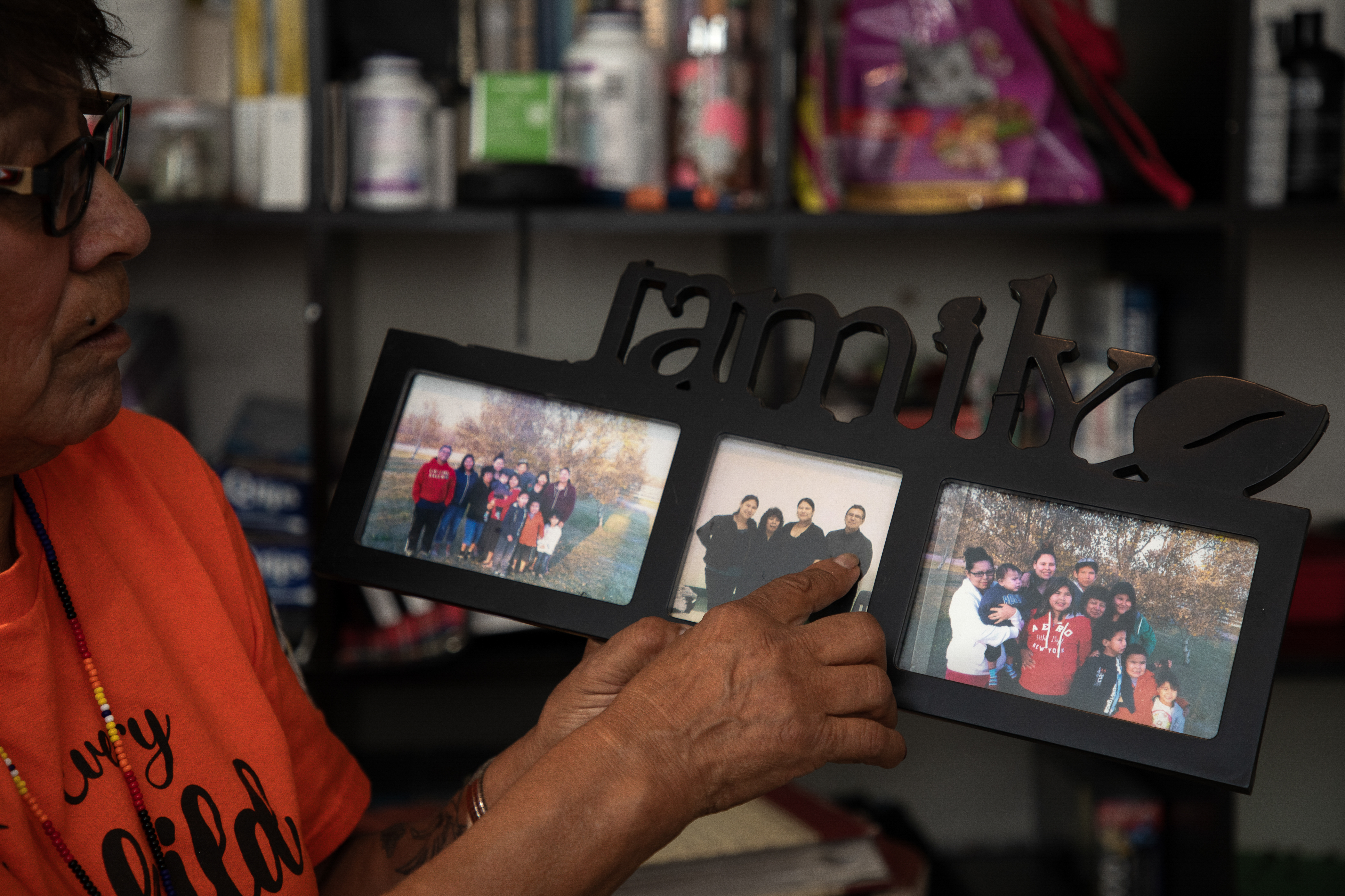 A woman points to family photos in a frame