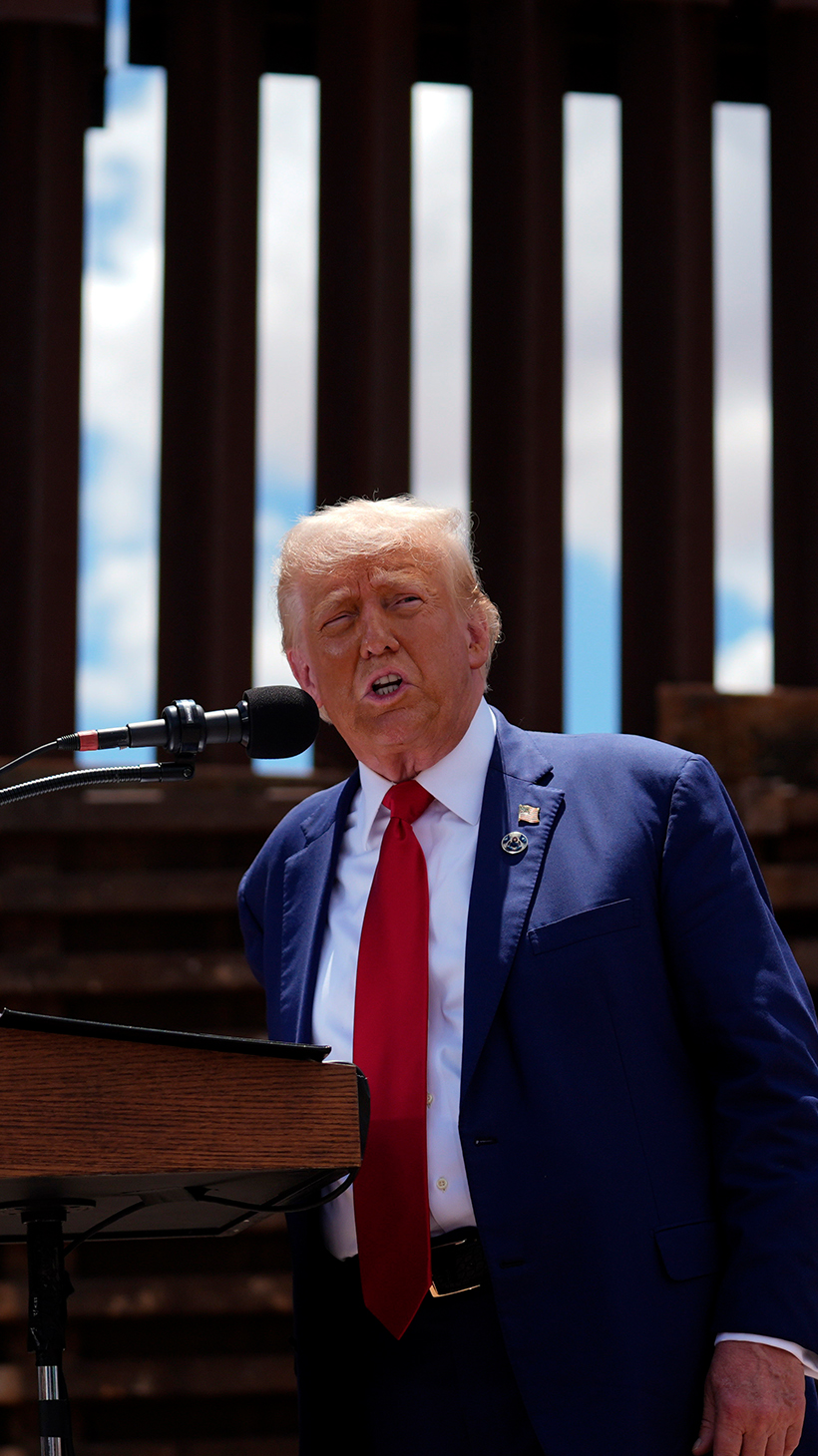 Donald Trump stands in front of the US-Mexico border wall