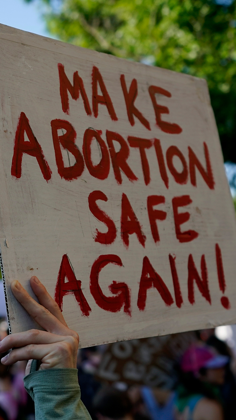 A protester holds up a sign that says, "Make Abortion Safe Again," as the Texas state capitol looms in the background.