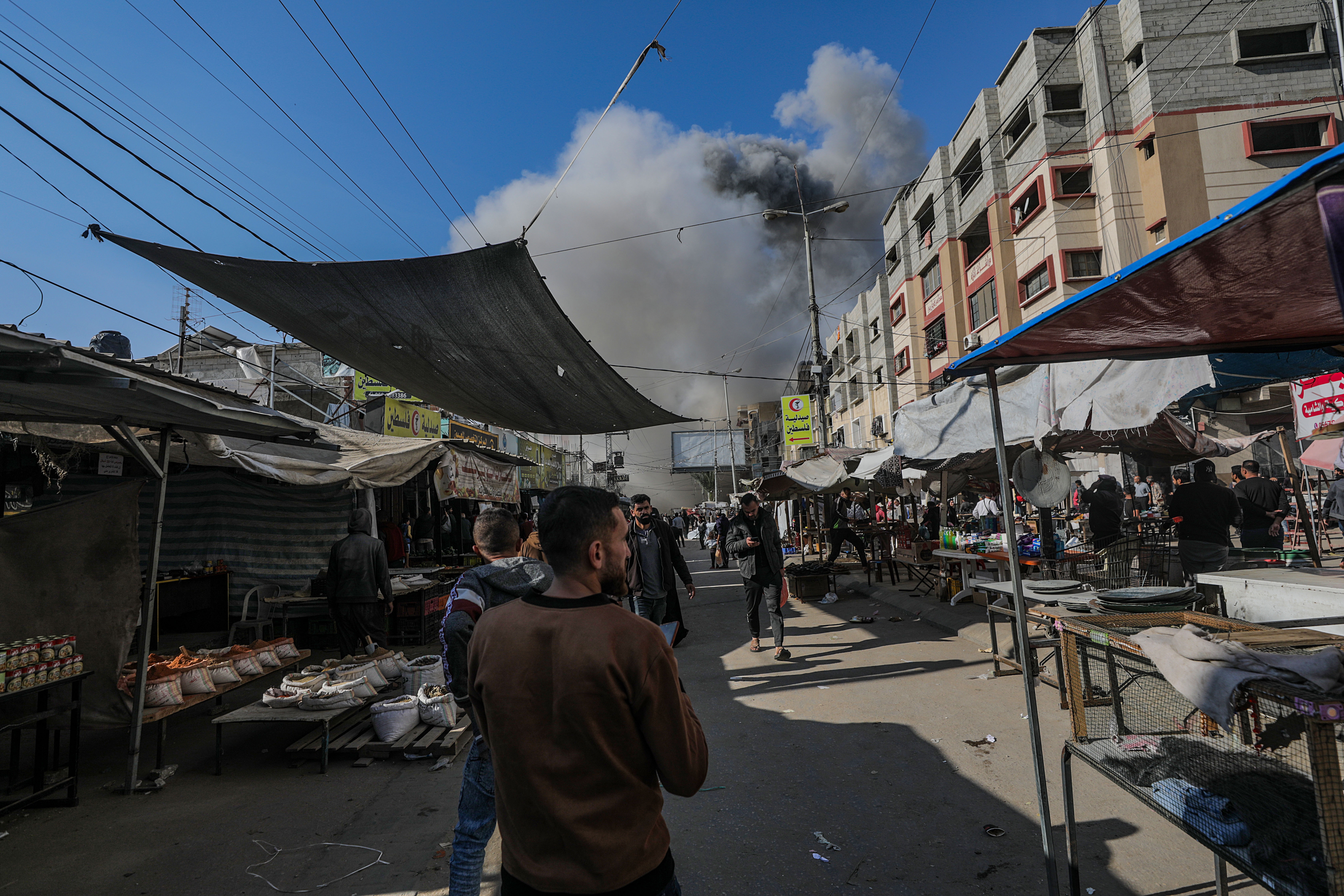Palestinians watch smoke rising during an Israeli attack on al-Faruq Mosque in the Nuseirat refugee camp, central Gaza Strip