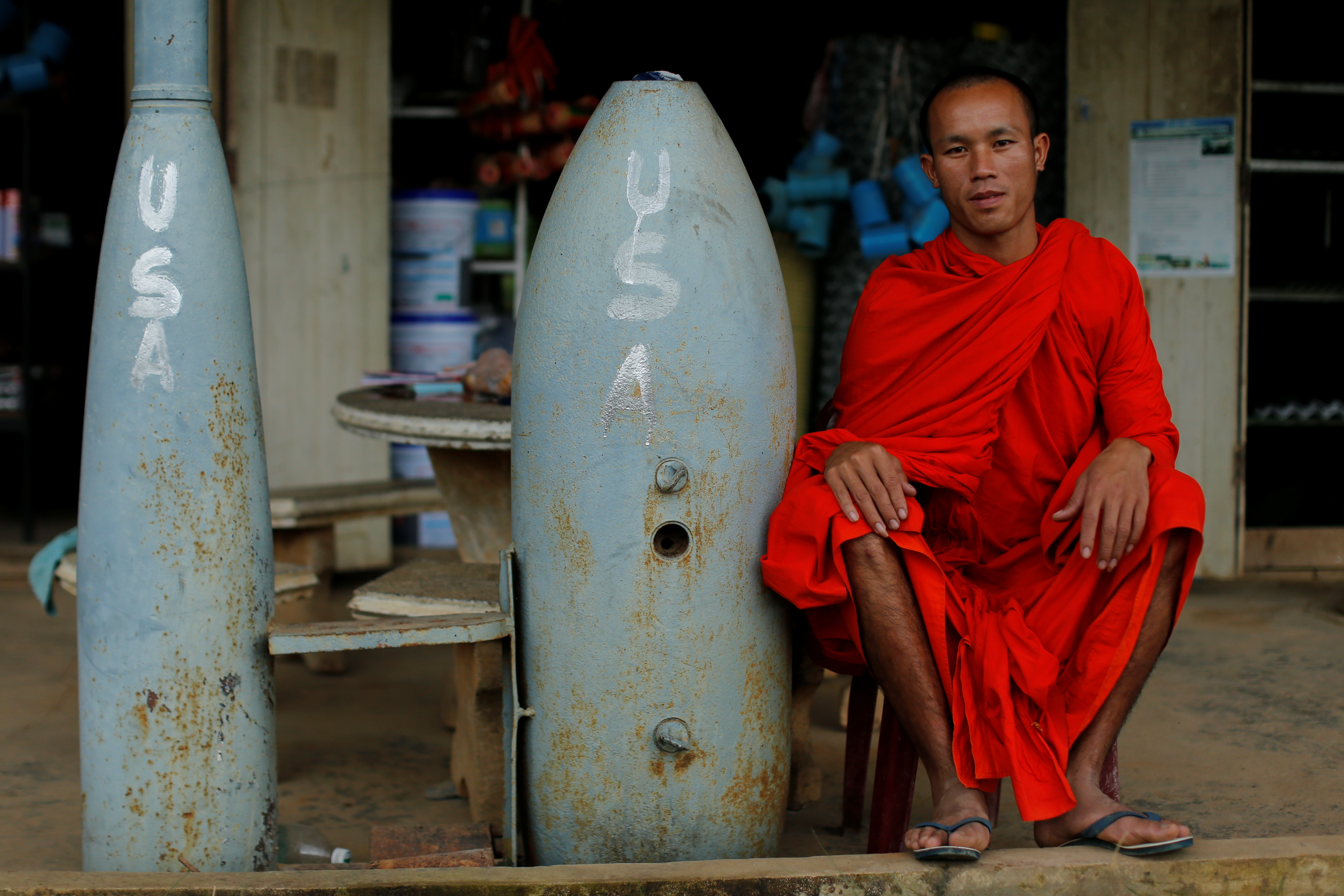 A Buddhist monk poses next to unexploded bombs dropped by the U.S. Air Force planes during the Vietnam War, in Xieng Khouang in Laos September 3, 2016. REUTERS/Jorge Silva SEARCH "LAOS BOMBS" FOR THIS STORY. SEARCH "WIDER IMAGE" FOR ALL STORIES. TPX IMAGES OF THE DAY