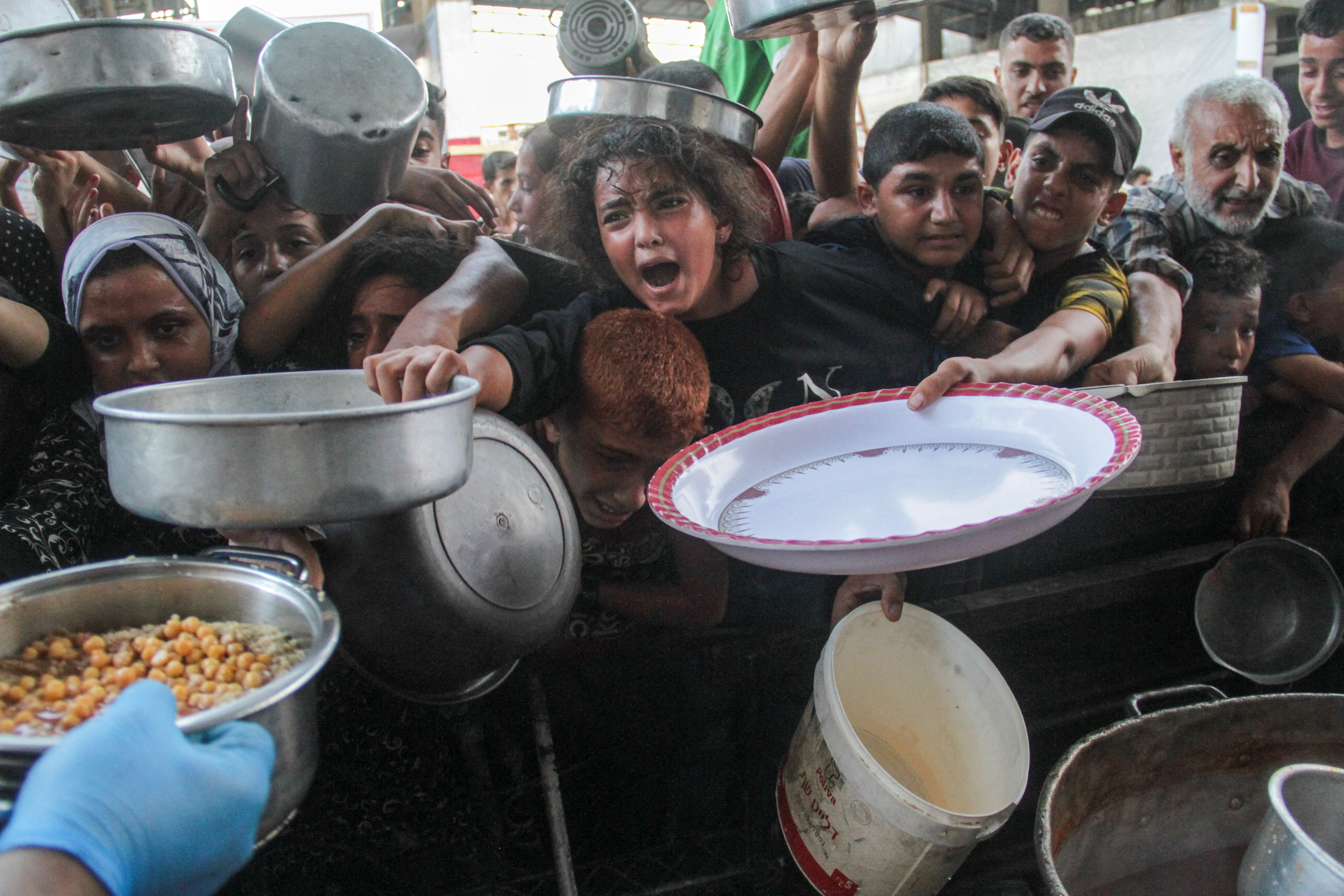 Palestinians crowd around to receive food cooked by a charity kitchen