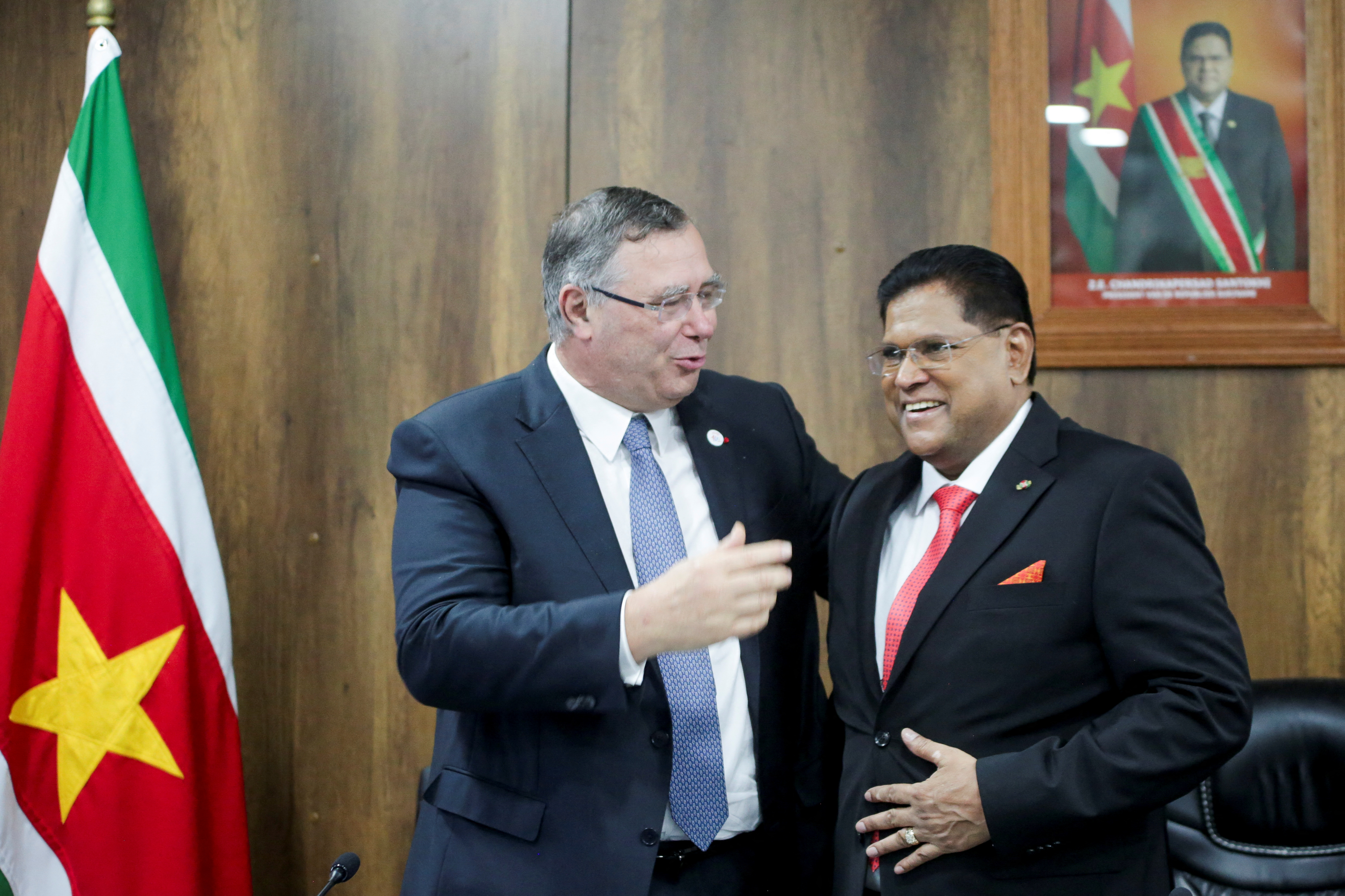 TotalEnergies CEO Patrick Pouyanne, left, and Suriname President Chan Santokhi embrace after France's TotalEnergies and US APA Corp announced they would invest in Suriname's most promising oil and gas project, Block 58 [Ranu Abhelakh/Reuters]
