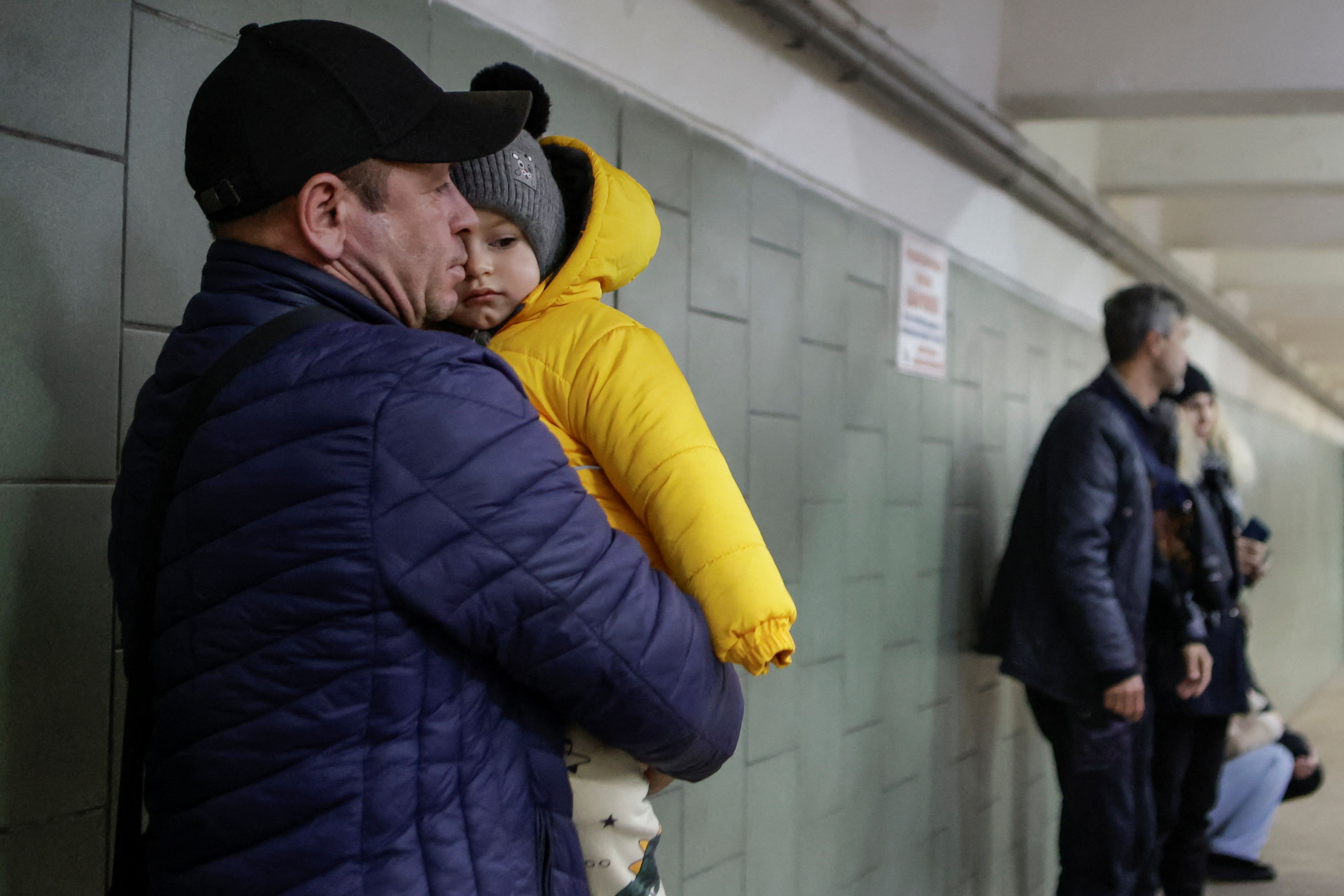 A resident holds a baby as he takes shelter inside an underground pass during a Russian air strike, amid Russia's attack on Ukraine, in Kharkiv, Ukraine November 8, 2024. REUTERS/Sofiia Gatilova