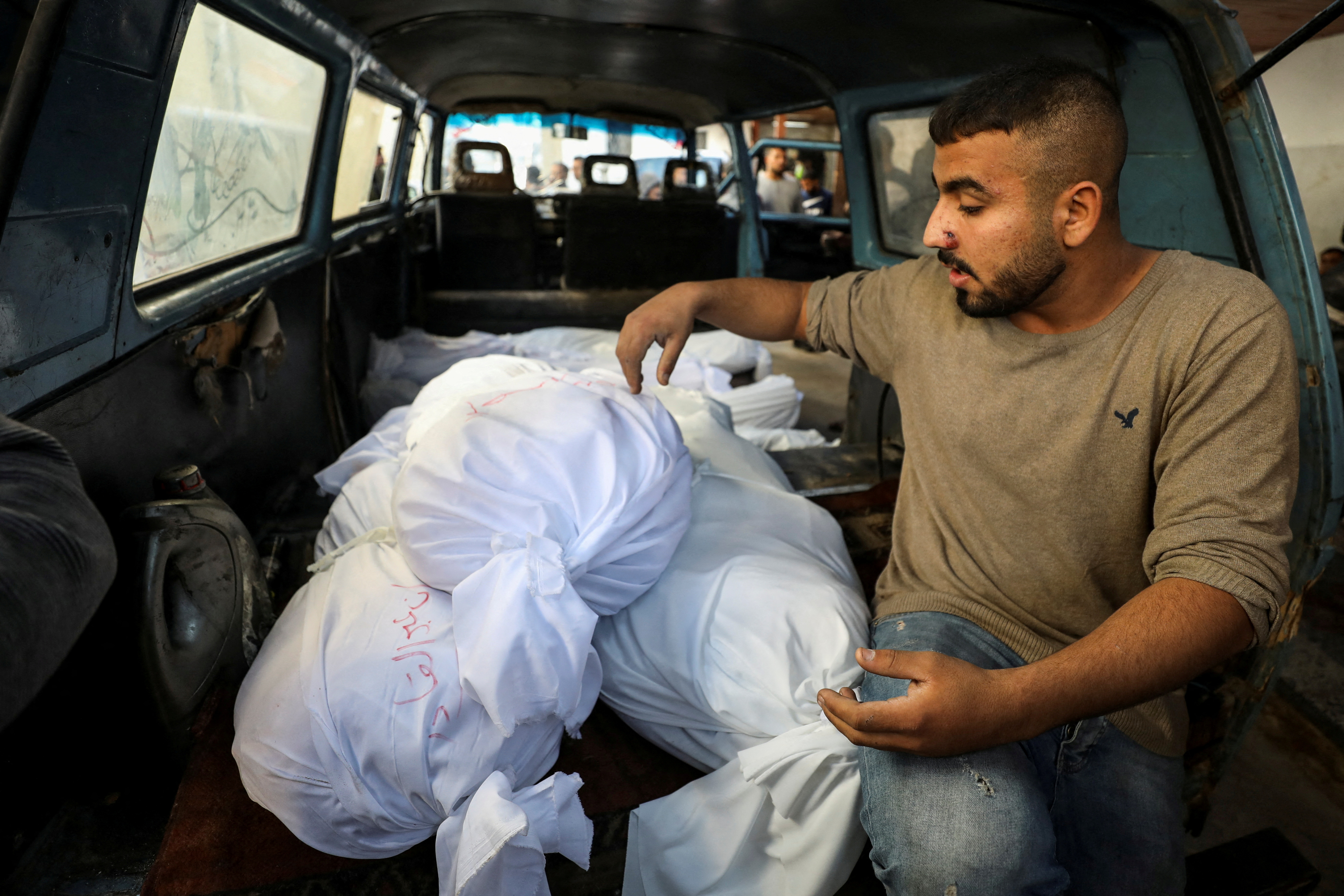 A person sits next to the bodies of Palestinians killed in an Israeli strike on a house in Jabalia