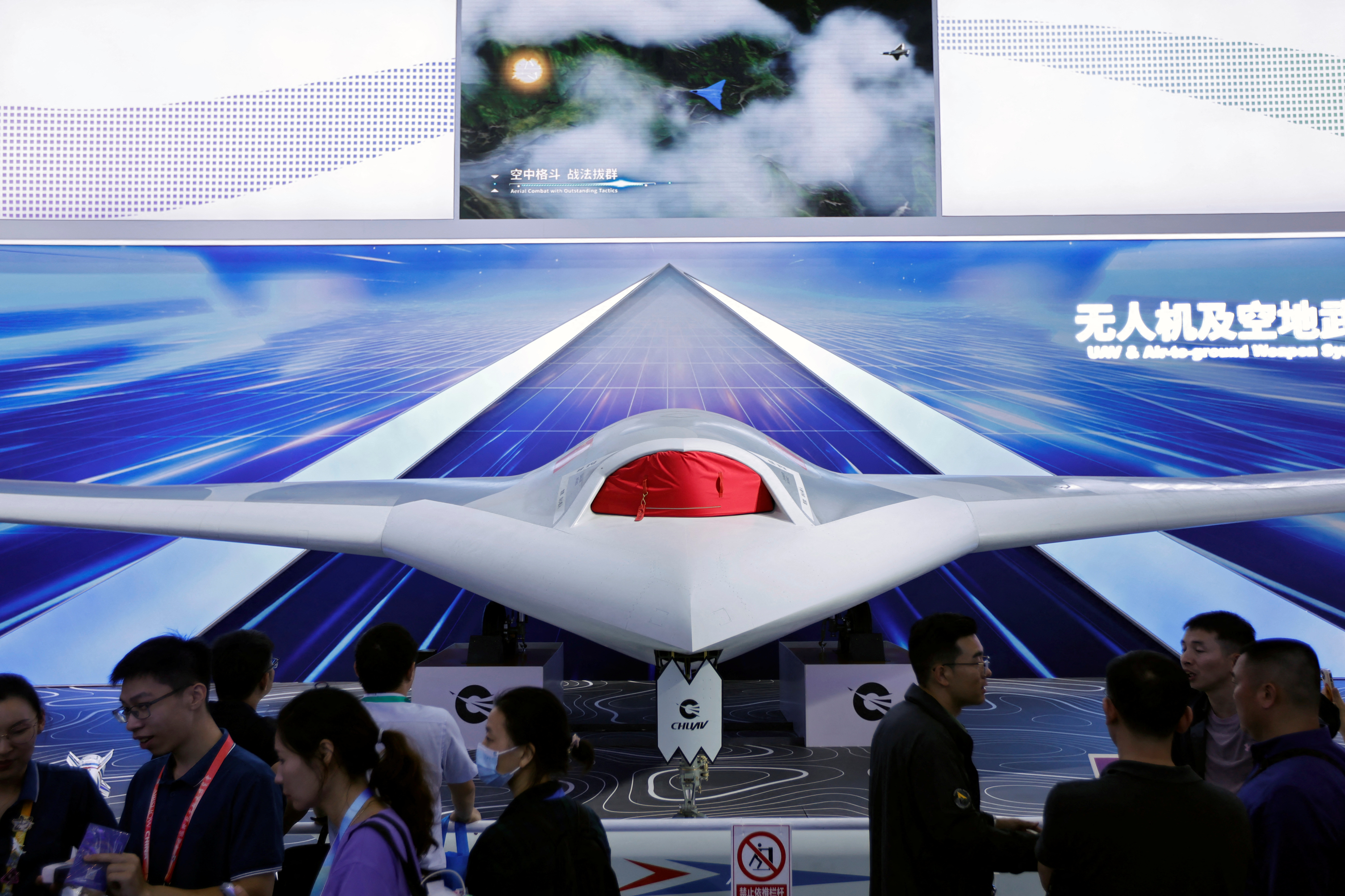Visitors stand near a model of the CH-7 stealthy unmanned aircraft at the China International Aviation and Aerospace Exhibition, or Airshow China, in Zhuhai, Guangdong province, China November 14, 2024. REUTERS/Tingshu Wang