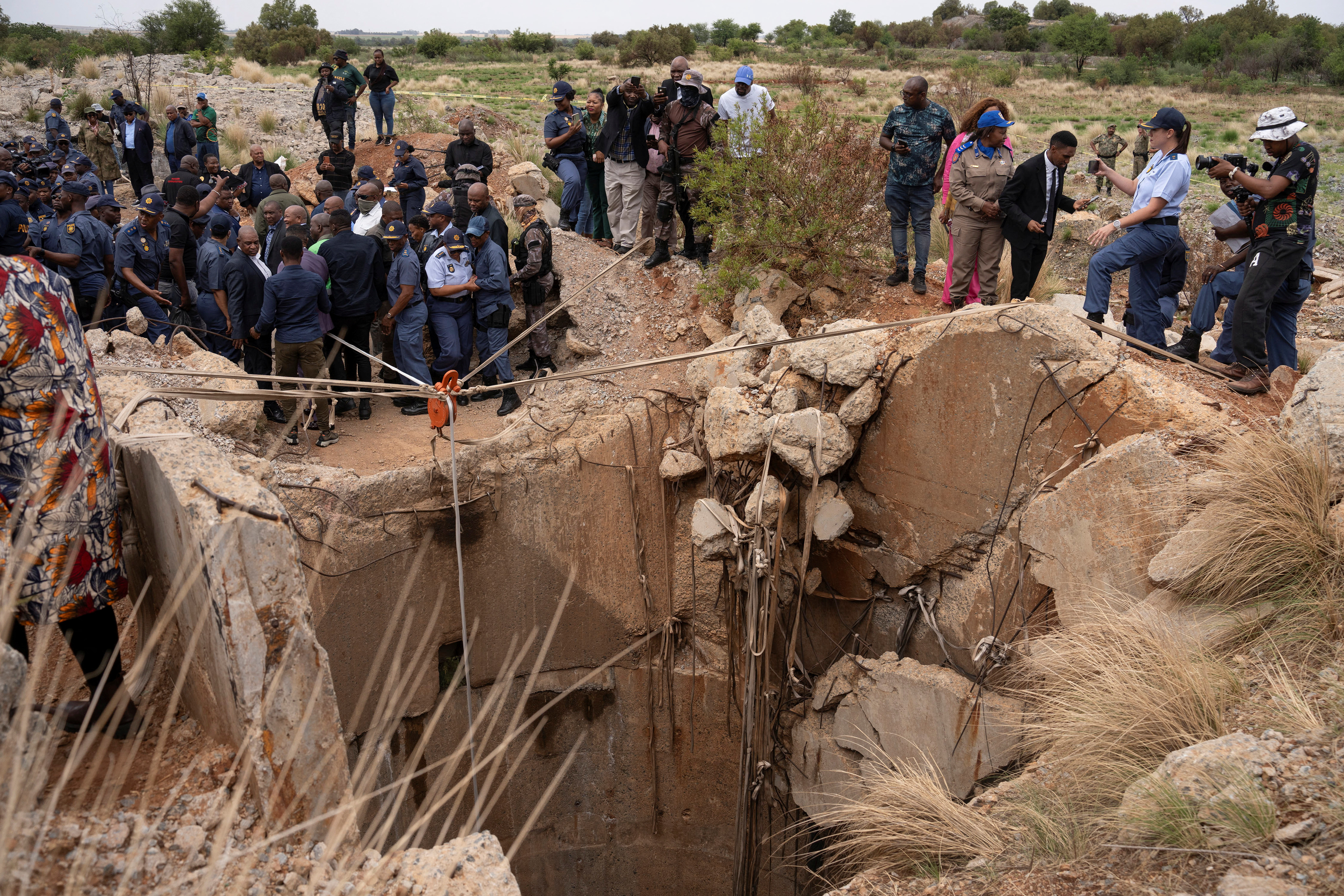 Community members watch as Senzo Mchunu, South Africa's police minister, inspects the outside of the mine shaft in Stilfontein