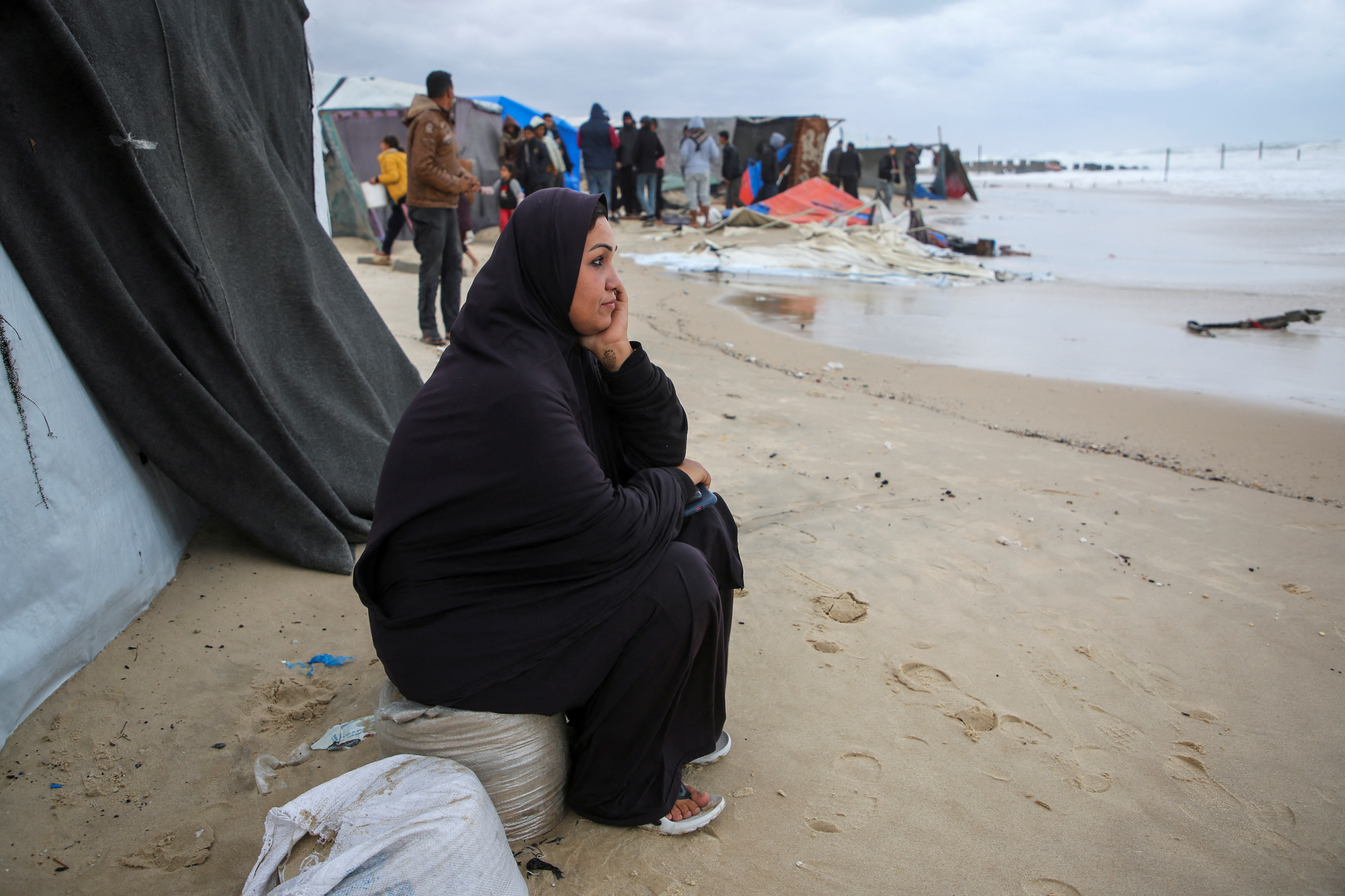 A displaced Palestinian woman sits outside a flooded tent following rising sea levels and heavy rainfall, amid the ongoing conflict between Israel and Hamas, in Khan Younis in the southern Gaza Strip, November 25, 2024. REUTERS/Hatem Khaled