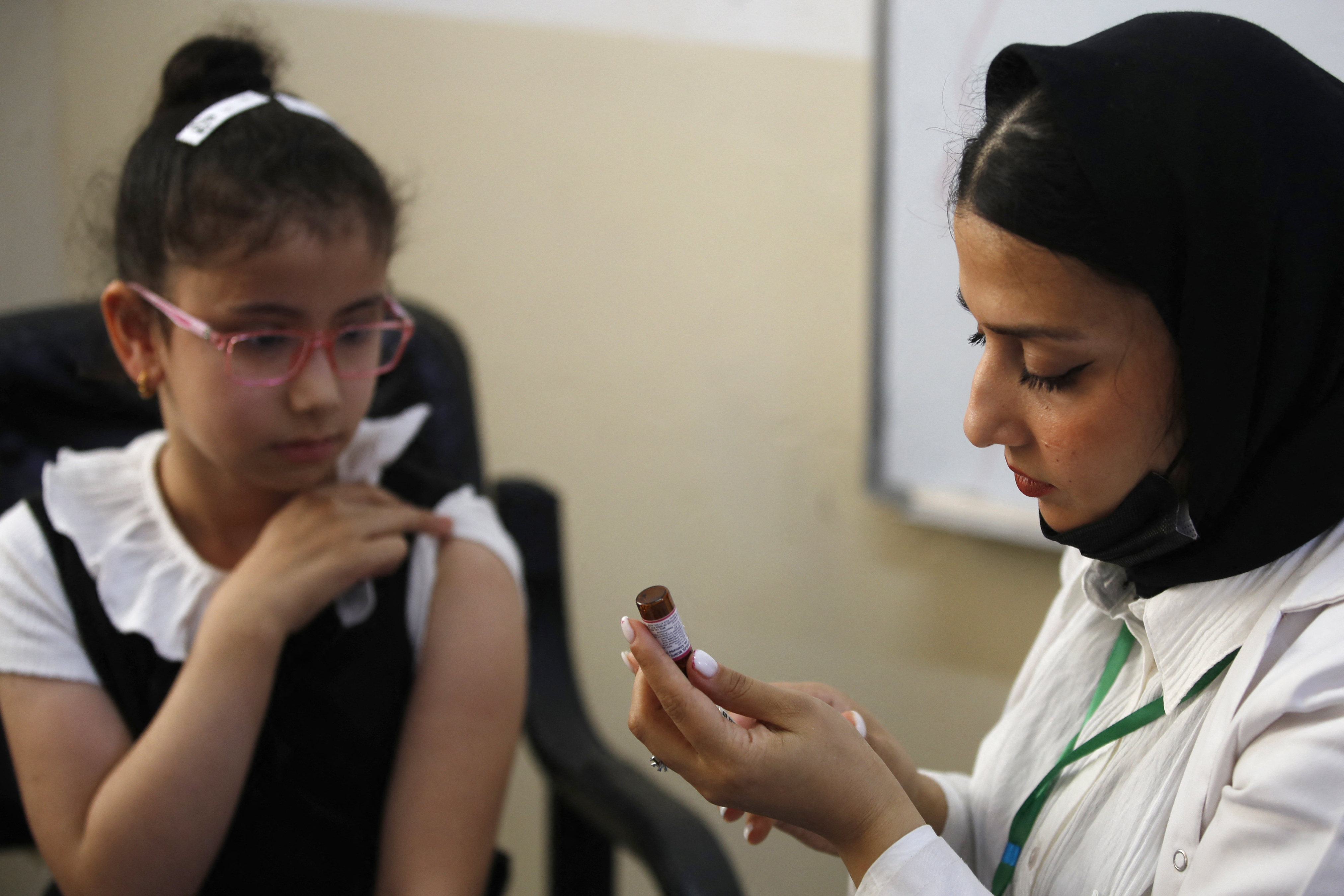 A schoolgirl receives a measles vaccine at a school in Baghdad, on April 14, 2024, part of a vaccination campaign for school students across Iraq. (Photo by AHMAD AL-RUBAYE / AFP)