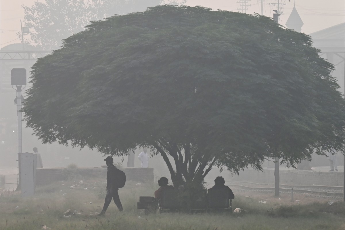 Passengers wait for a train at a railway station amid smoggy conditions in Lahore