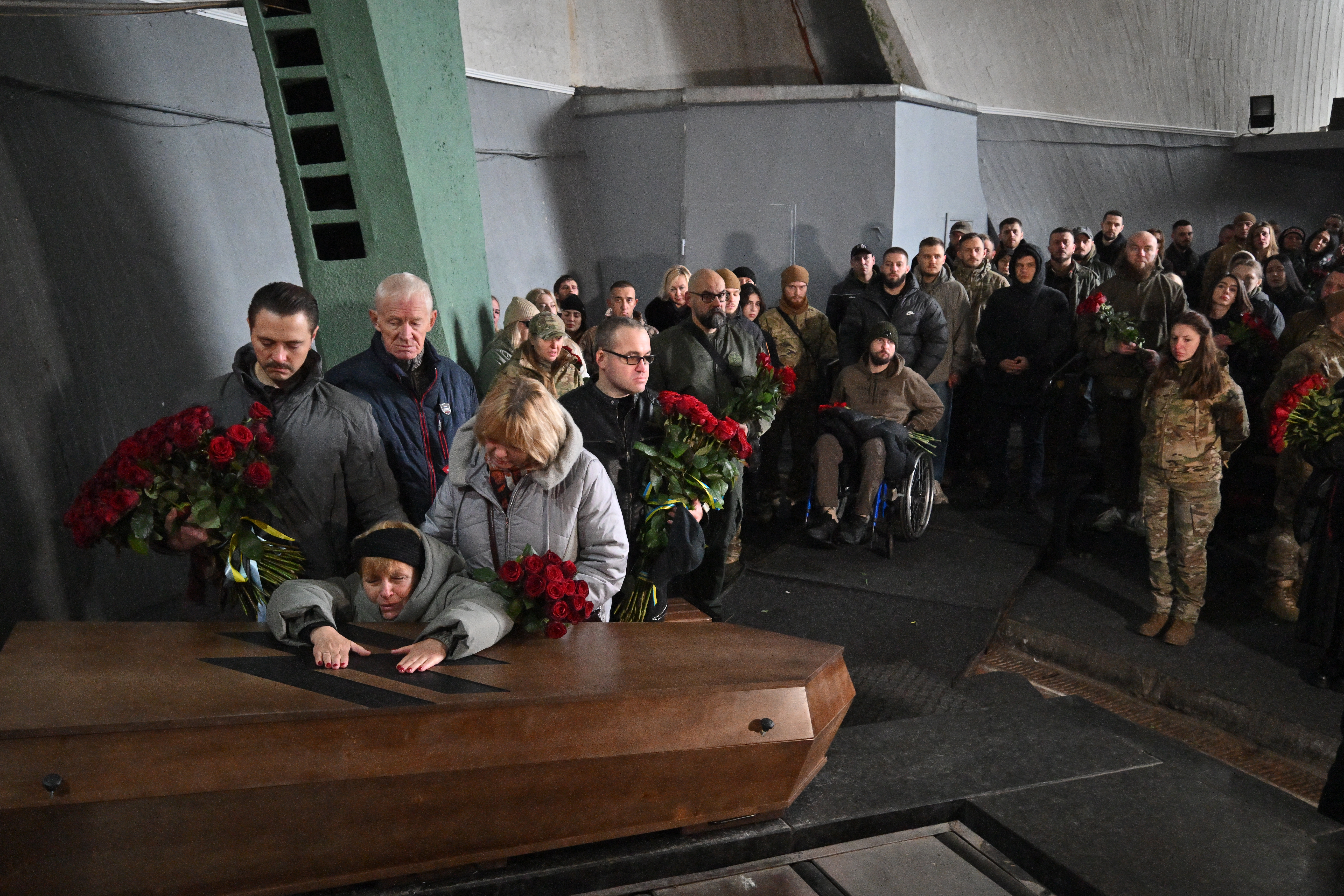TOPSHOT - Relatives and colleagues react in front of the coffin of military medic Valentyna Nagorna inside a Baikove crematorium in Kyiv during mourning ceremony on November 8, 2024. Hundreds gathered in the biting cold in Kyiv to mourn military medic Valentyna Nagorna and soldier Daniil Liashkevych, who fell in love during the war and died together. (Photo by Sergei SUPINSKY / AFP)