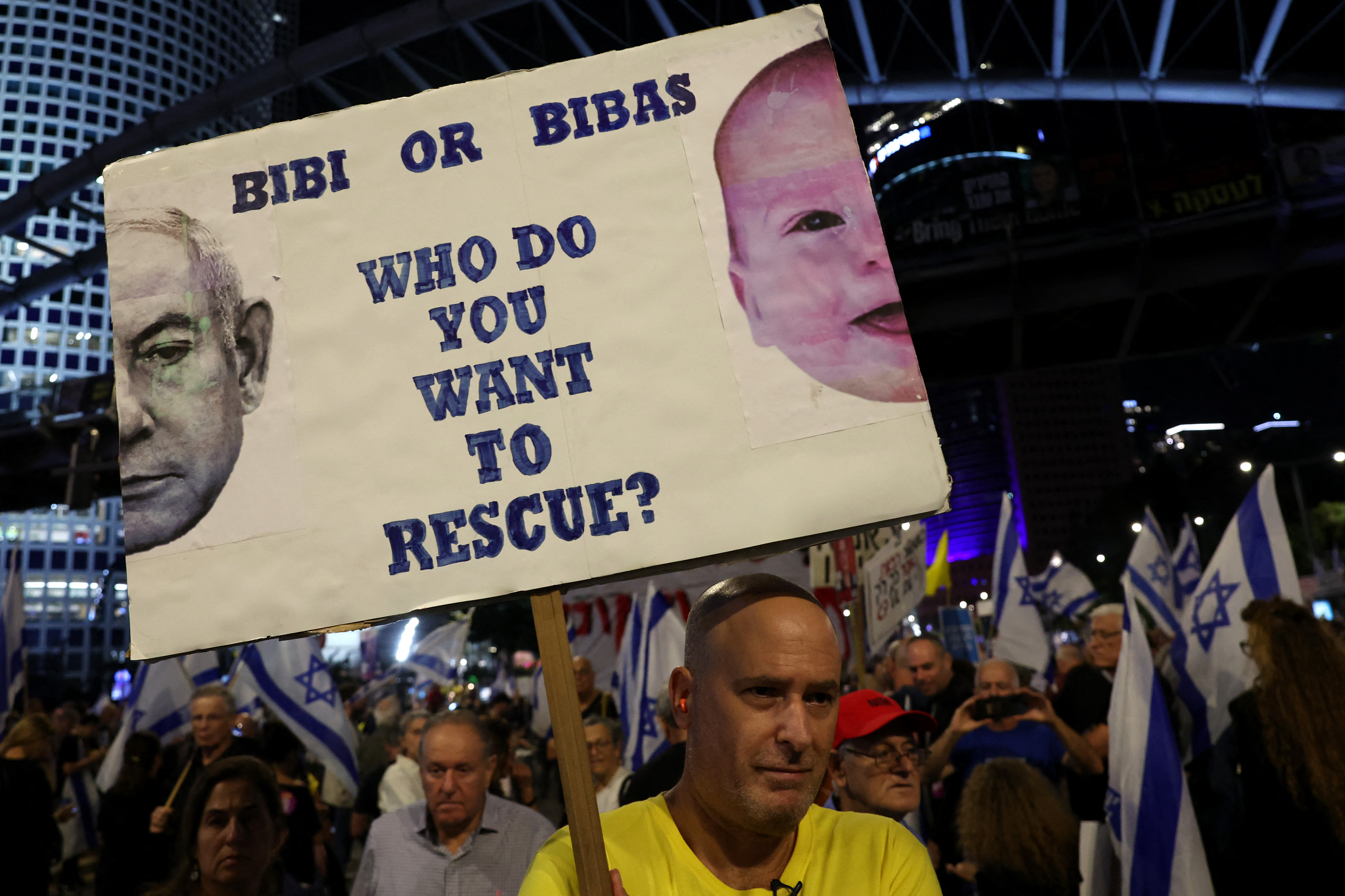 A man holds a sign displaying a slogan with pictures of Israel's Prime Minister Benjamin Netanyahu and a baby of the Bibas family, Israeli hostages still believed to be held in the Gaza Strip since the October 7 attack by Hamas, during a rally in Tel Aviv calling for the release of the kidnapped, on November 9, 2024, amid the ongoing war between Israel and the militant Hamas group in the Palestinian territory. (Photo by Jack GUEZ / AFP)