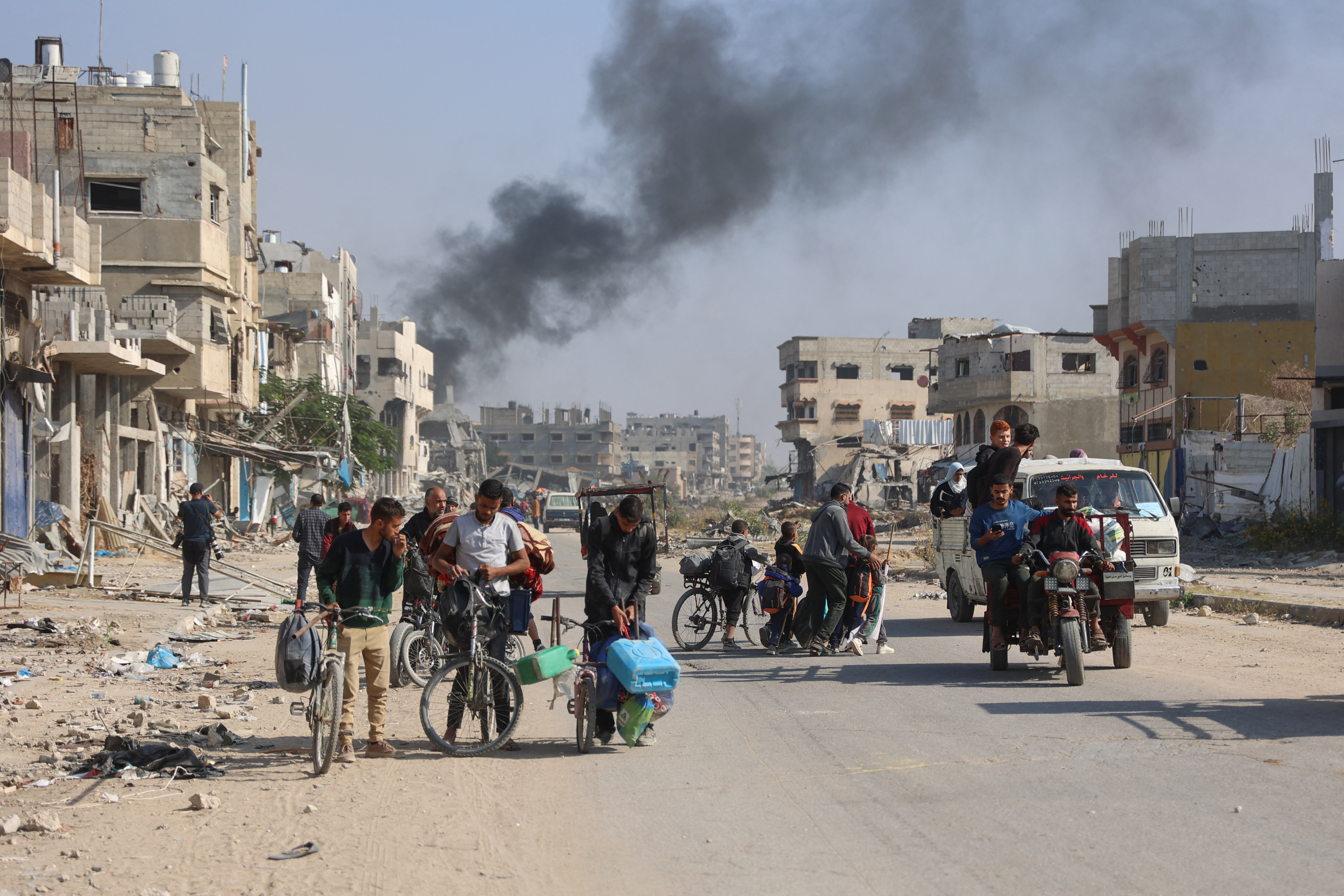 Palestinians displaced from shelters in Beit Hanoun cross the main Salaheddine road into Jabalia in the northern Gaza Strip on bicycles and tuk-tuks following Israeli army evacuation orders