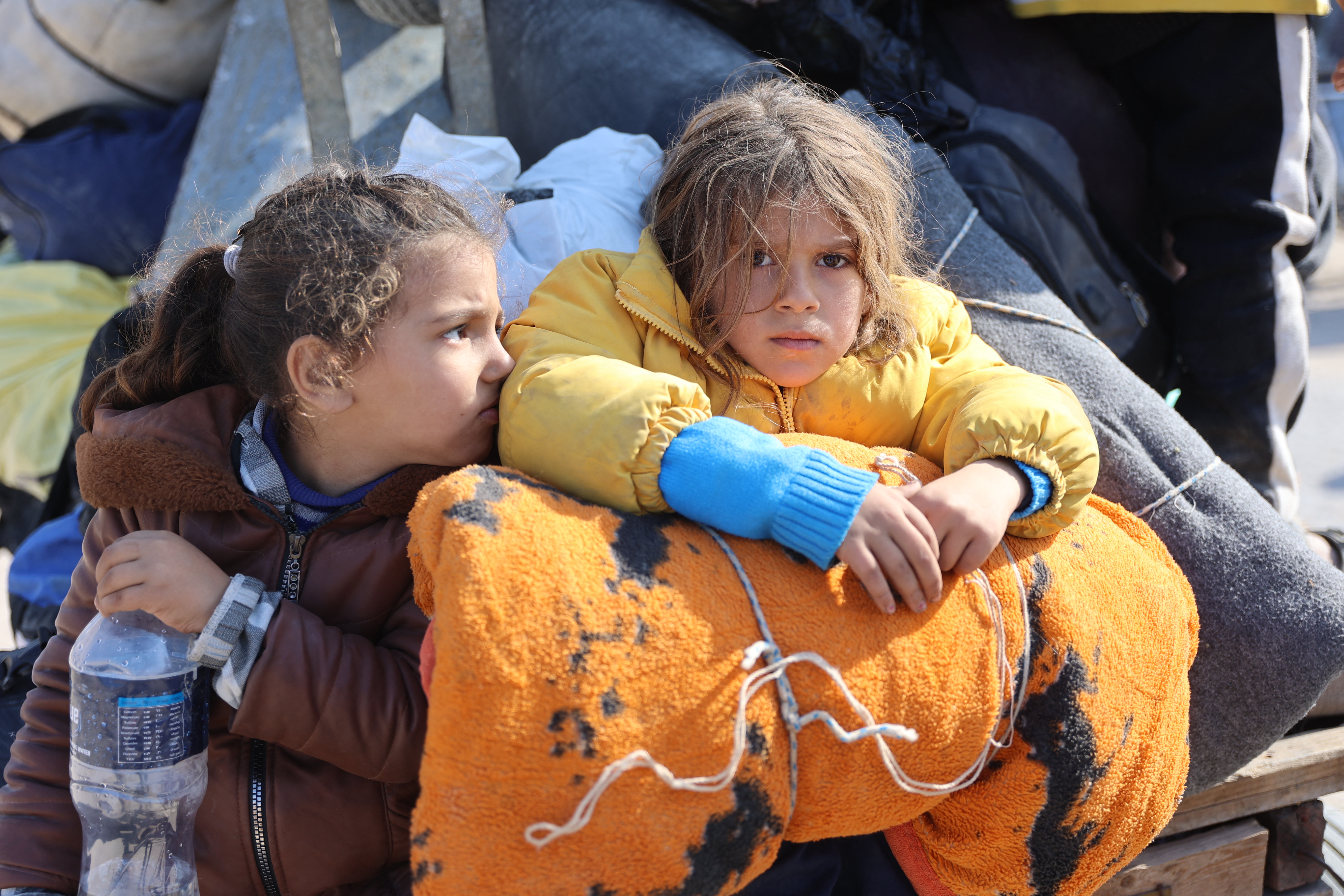 Children sit in the back of a donkey cart as Palestinians displaced from shelters in Beit Hanoun cross the main Salaheddine road into Jabalia in the northern Gaza Strip