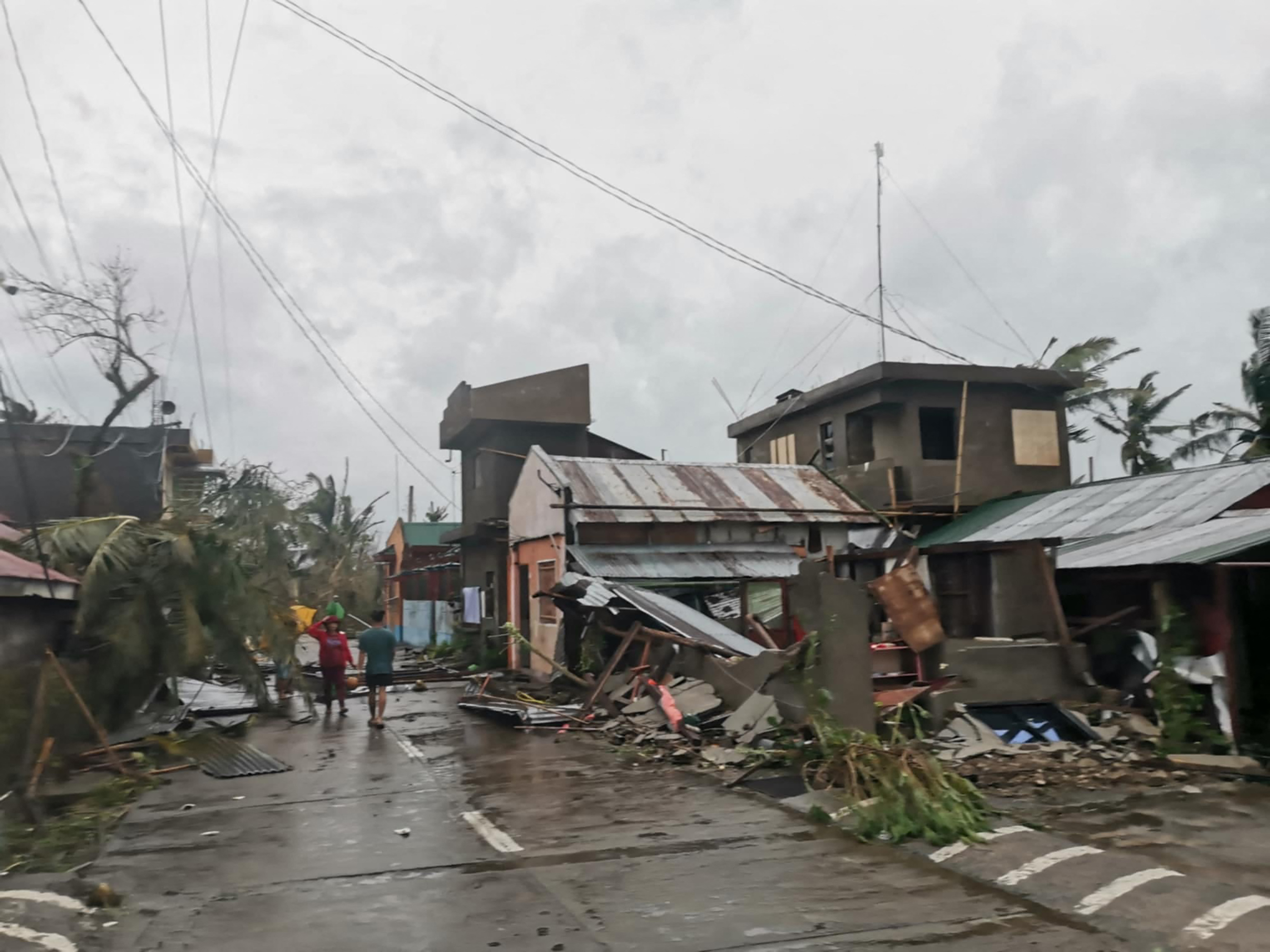 Residents walk past destroyed houses in Panganiban town in the island province of Catanduanes after the Category 5 Super Typhoon Man-yi hit overnight