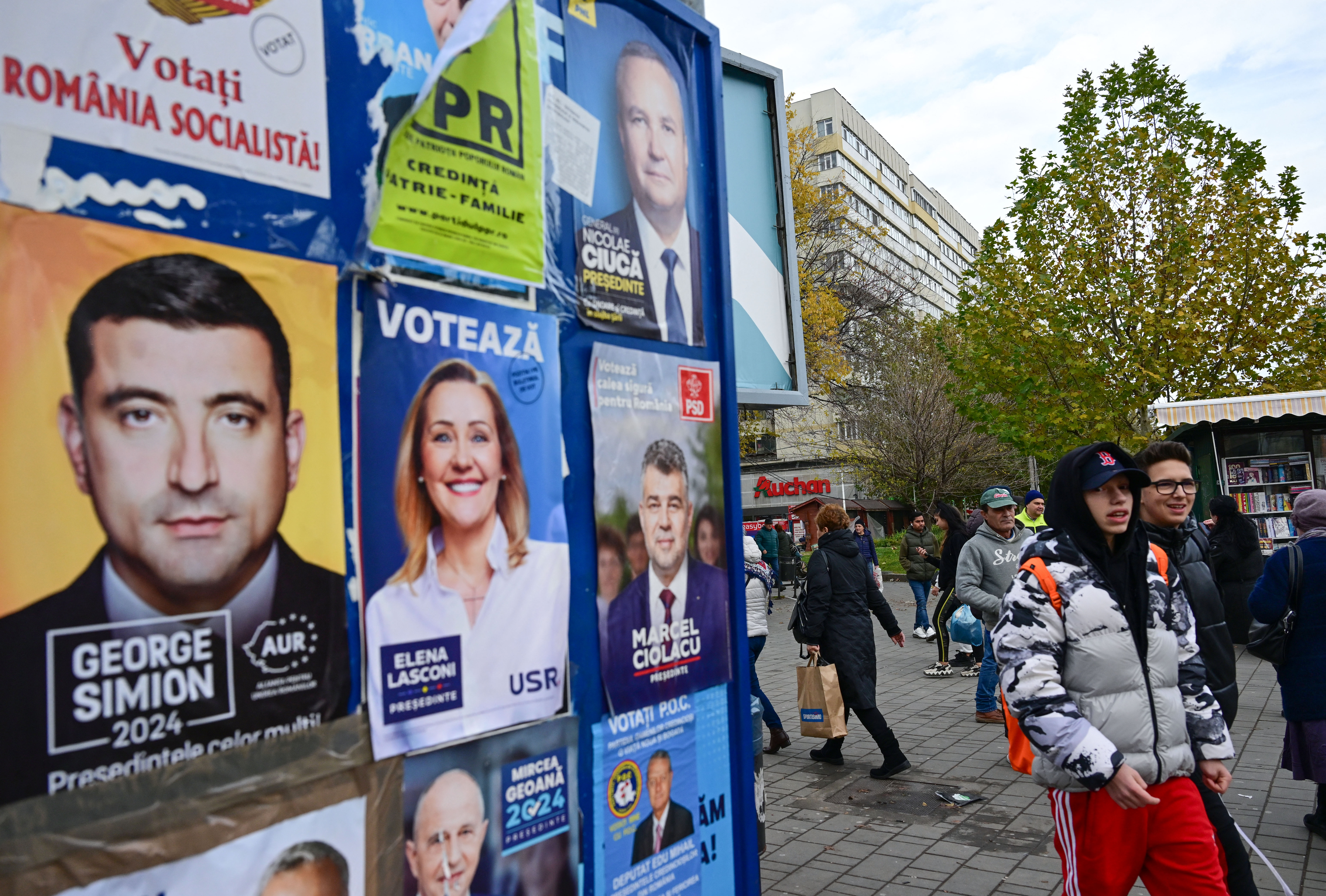 People pass by political posters on November 22, 2024. [Daniel Mihailescu / AFP]