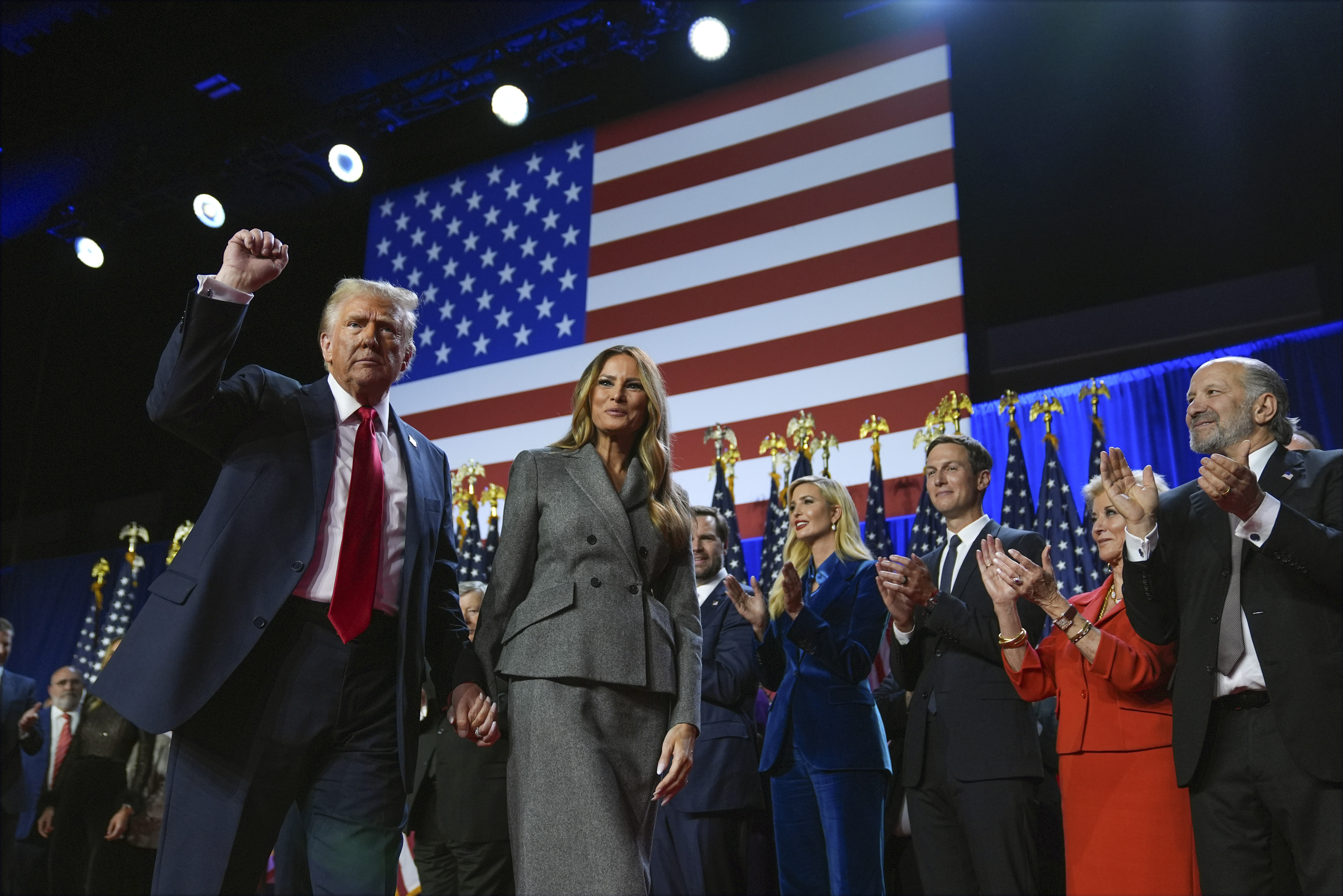 Republican presidential nominee former President Donald Trump gestures as he walks with former first lady Melania Trump at an election night watch party at the Palm Beach Convention Center, Wednesday, Nov. 6