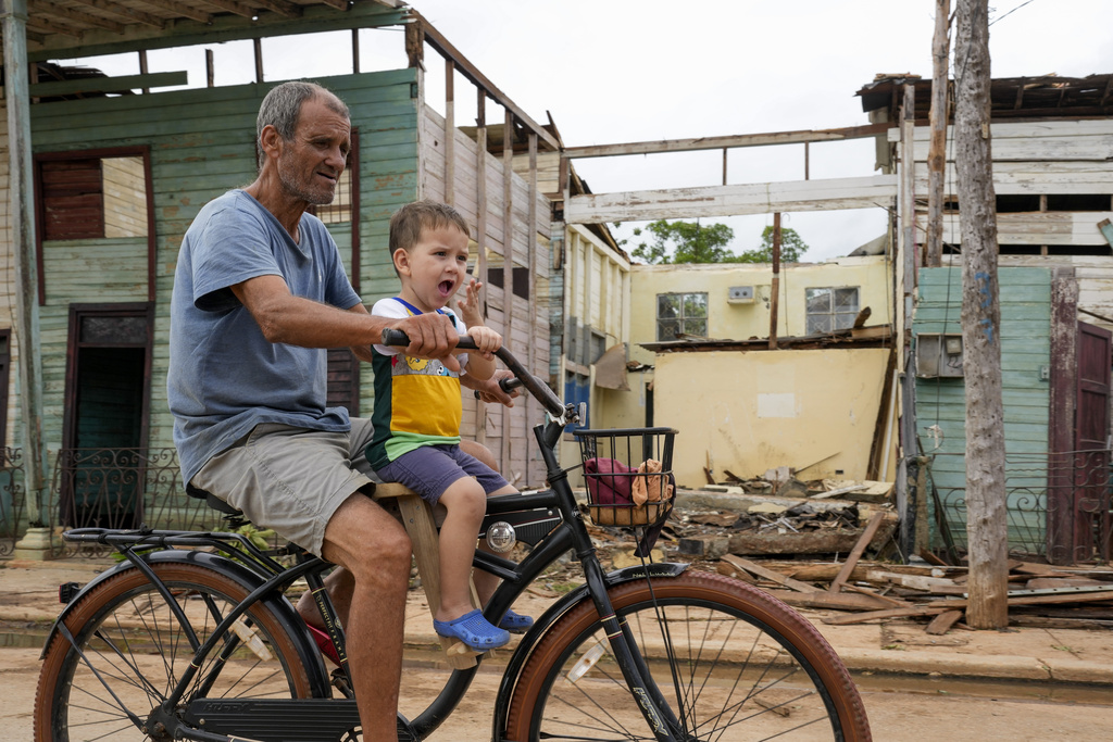 Residents bike past buildings damaged by a storm