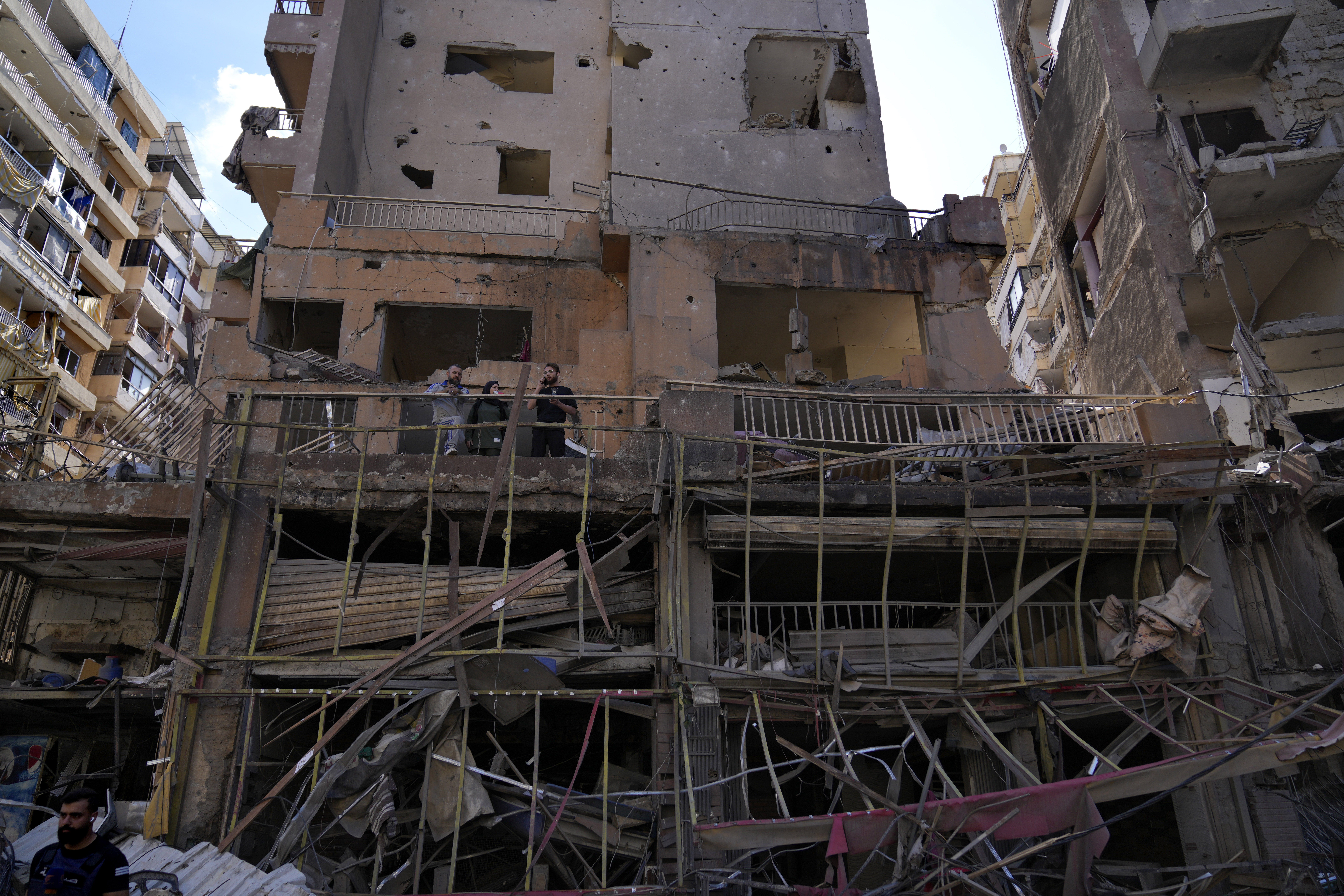 Residents stand on their apartment balcony at a building that was destroyed by an Israeli airstrike in Dahiyeh, in the southern suburb of Beirut