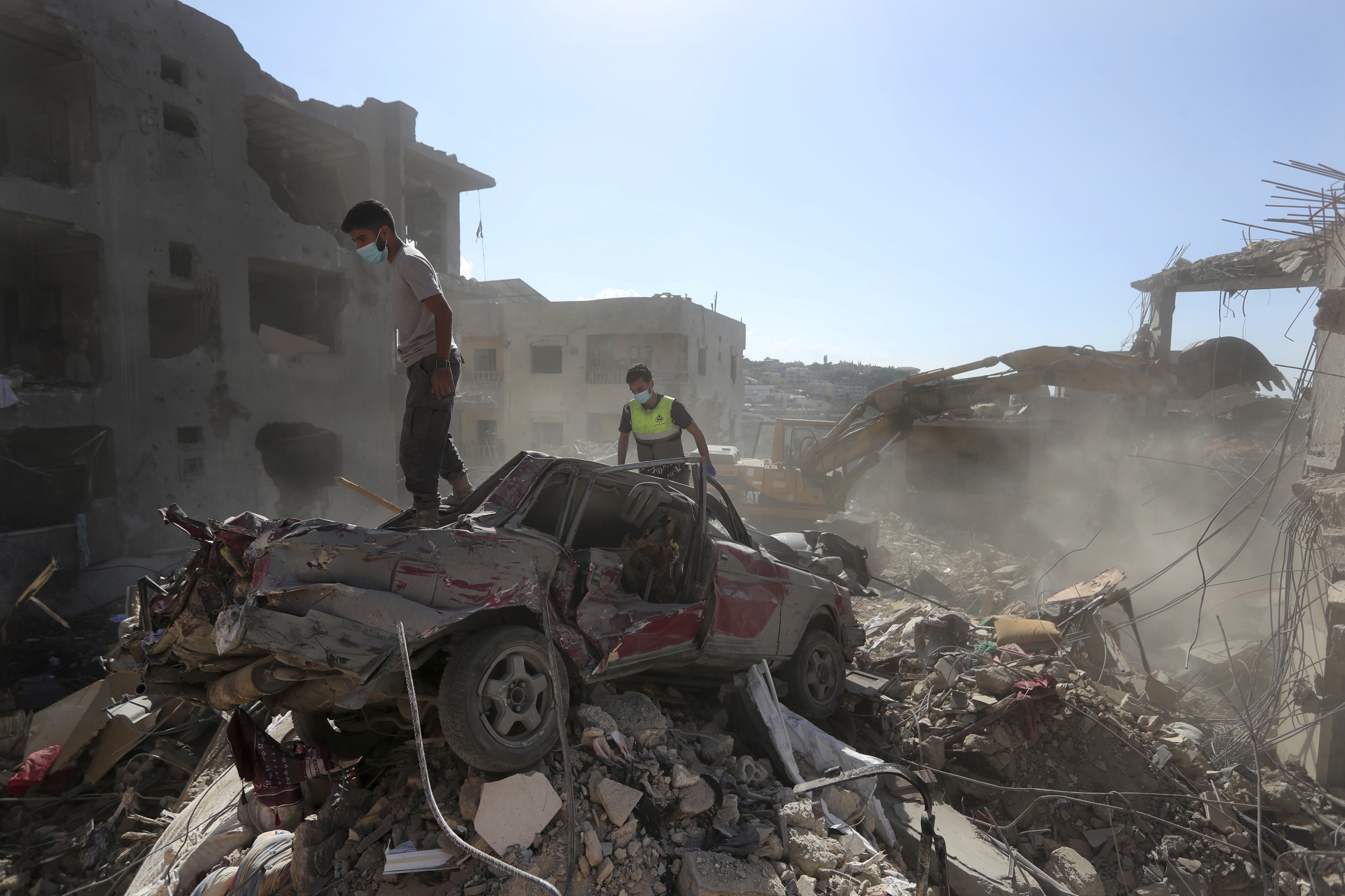 Rescue worker stand on a destroyed car over the rubble of a destroyed