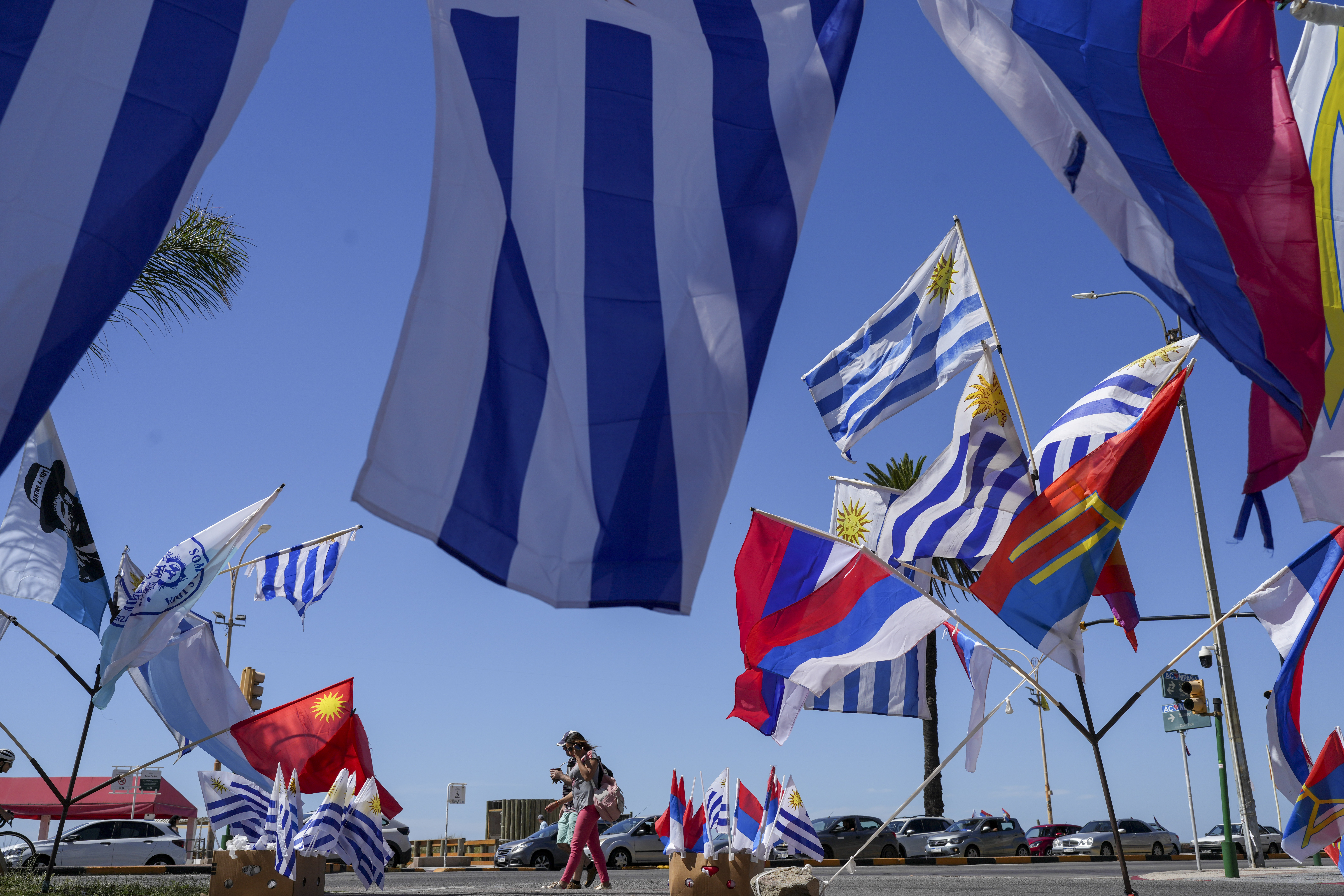 Uruguay flags hang for sale in front of a parking lot.