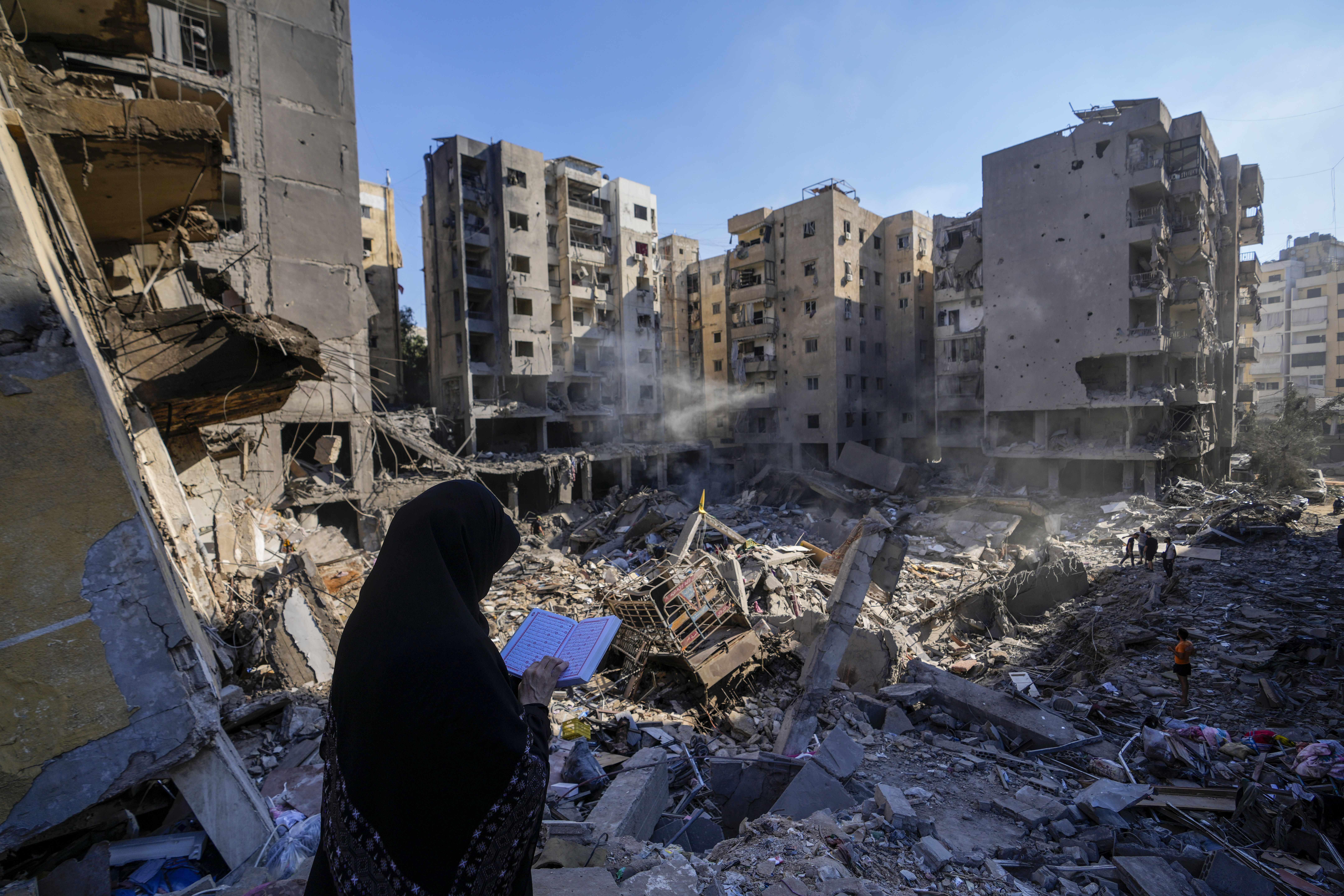 A woman reads the Quran at the site of the assassination of Hezbollah leader Hassan Nasrallah in Beirut's southern suburbs